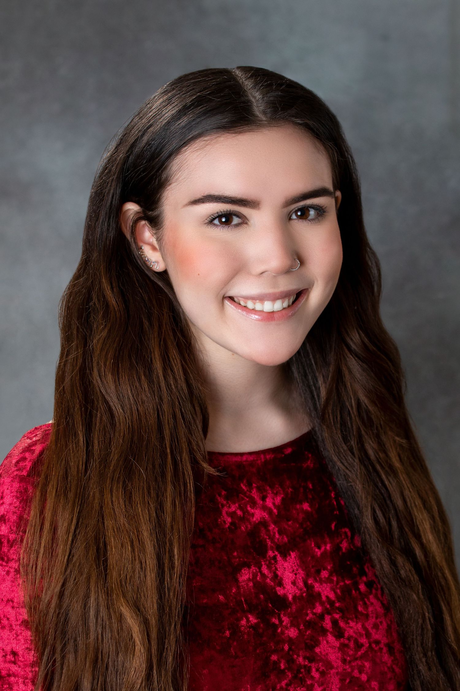 Progressive headshots in red velvet top showing bright smiles against grey backdrop.