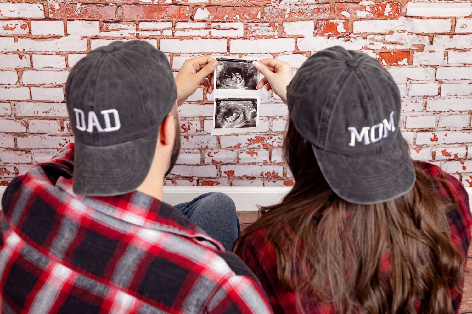 A couple in matching plaid shirts and baseball caps pose against a brick wall in a series of candid shots.