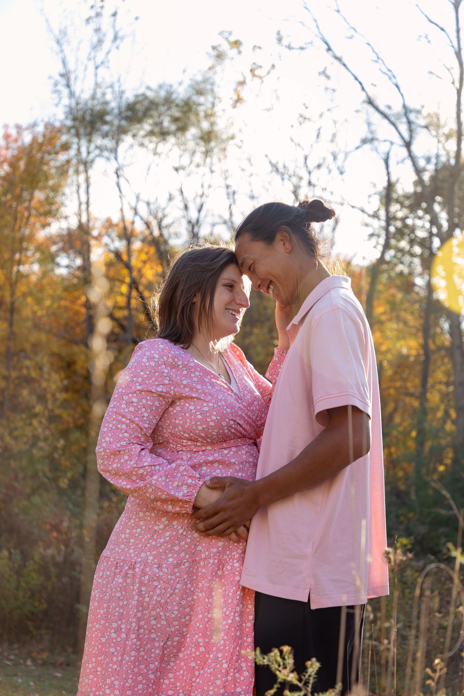 A loving couple shares an intimate moment during their maternity photoshoot in an autumn setting.