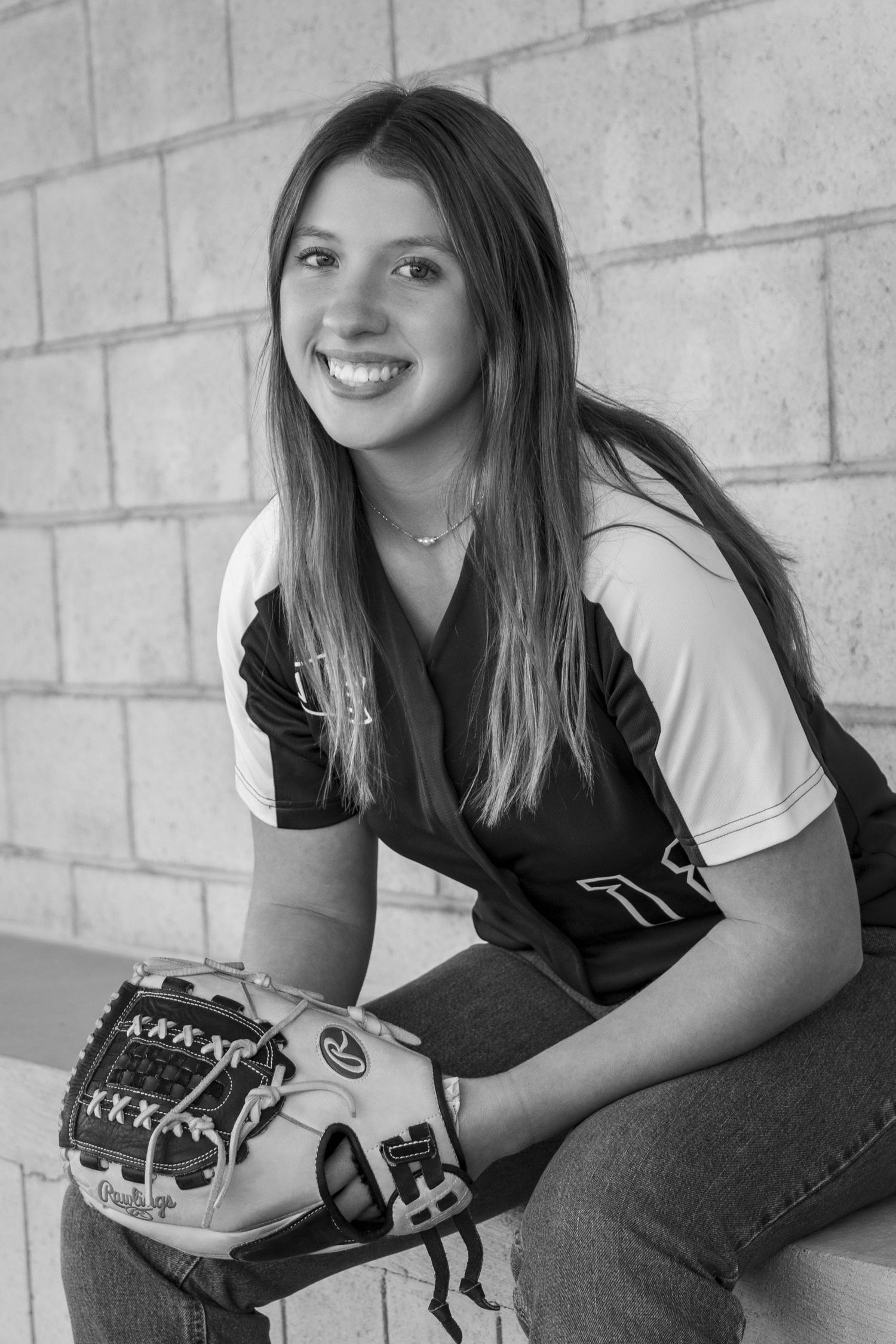 Black and white sports portrait featuring softball equipment against concrete wall background.