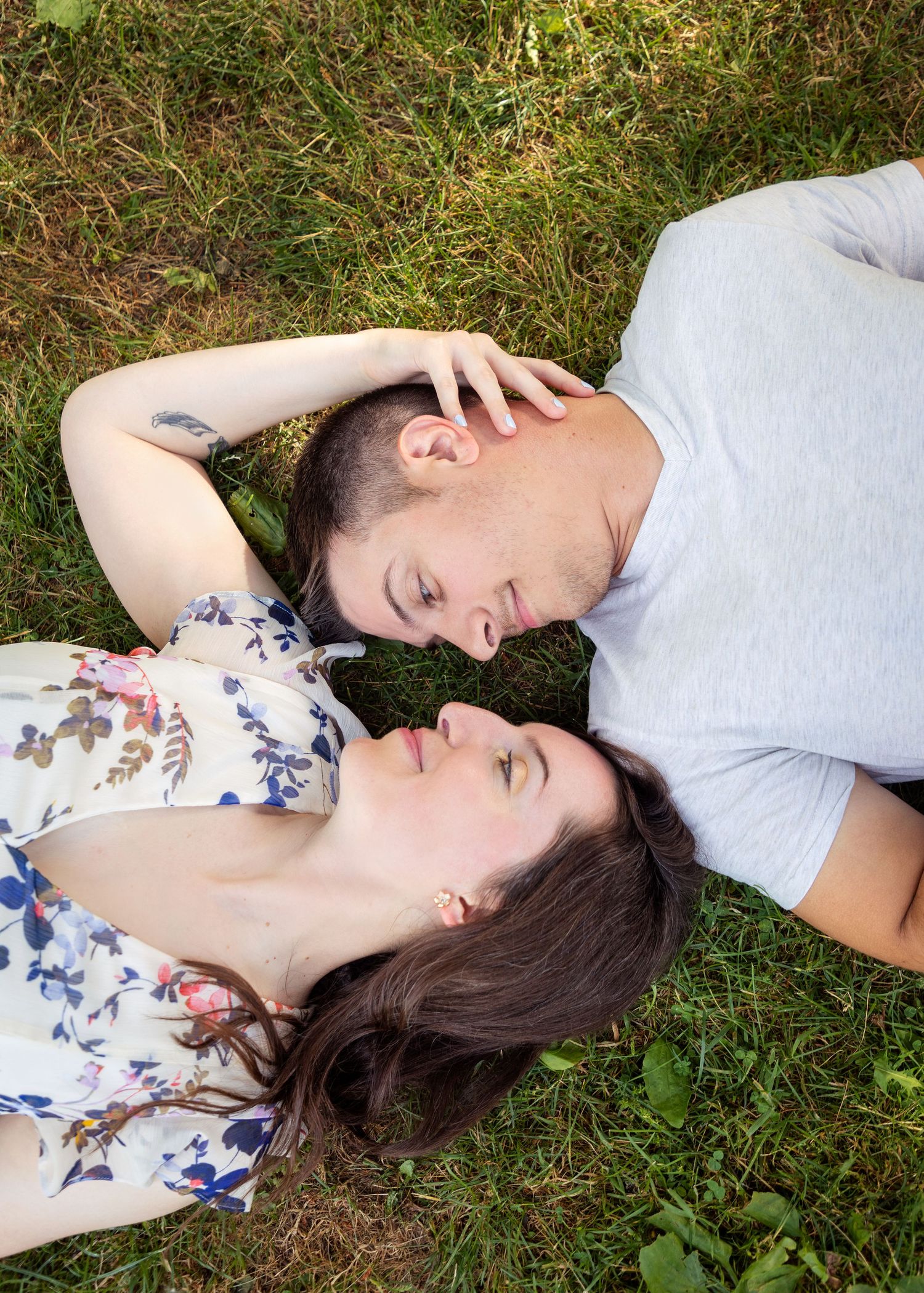 A couple lies in the grass during a romantic outdoor photoshoot.