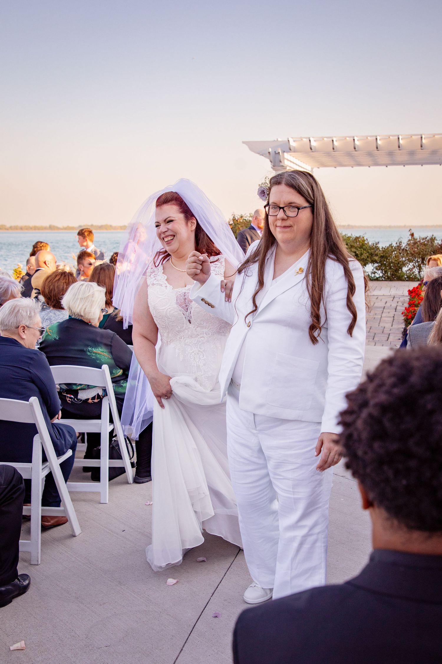 Wedding celebration with guests dancing and laughing together at an outdoor venue during sunset.