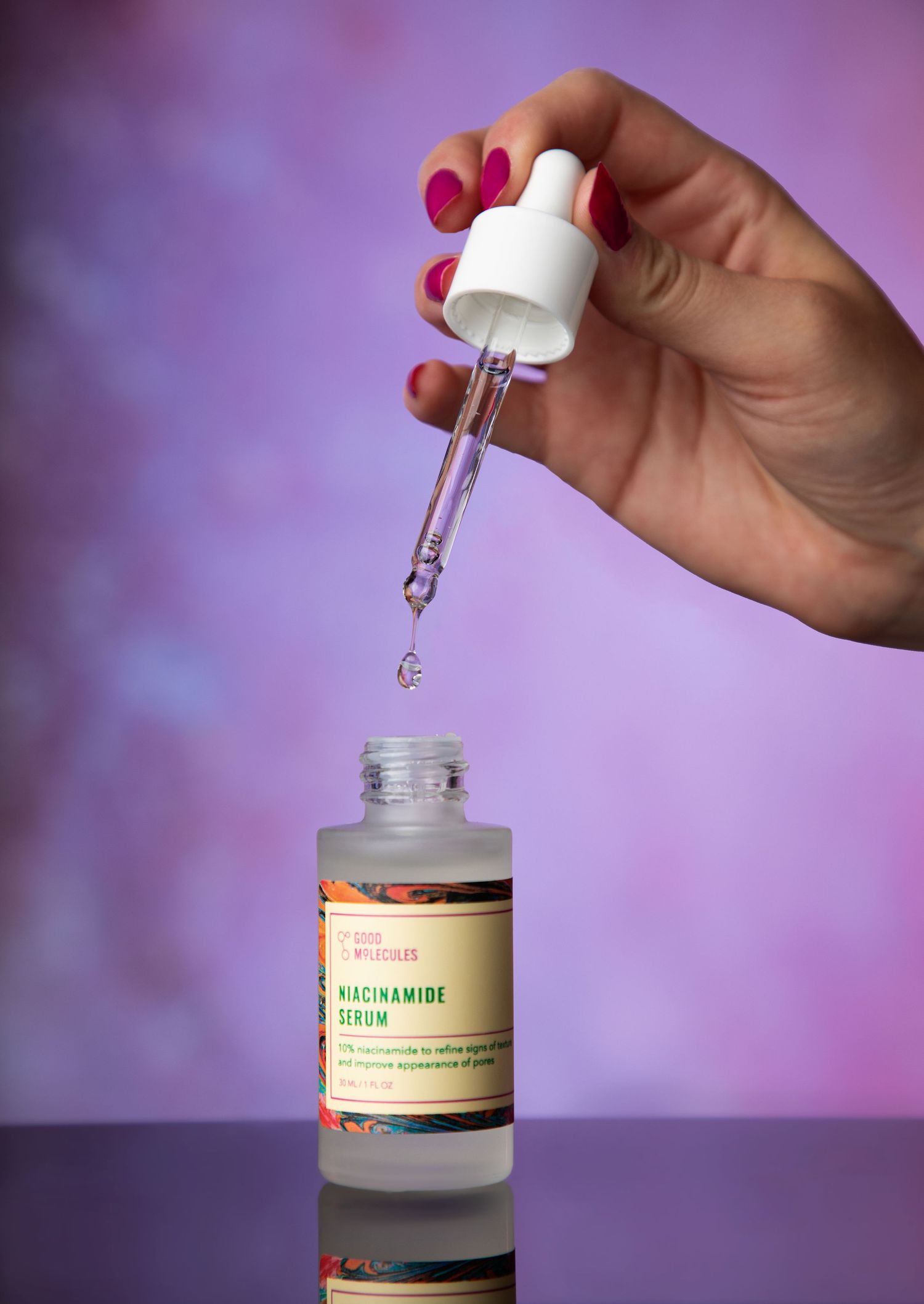 Dropper bottle of skincare serum being opened against purple background.