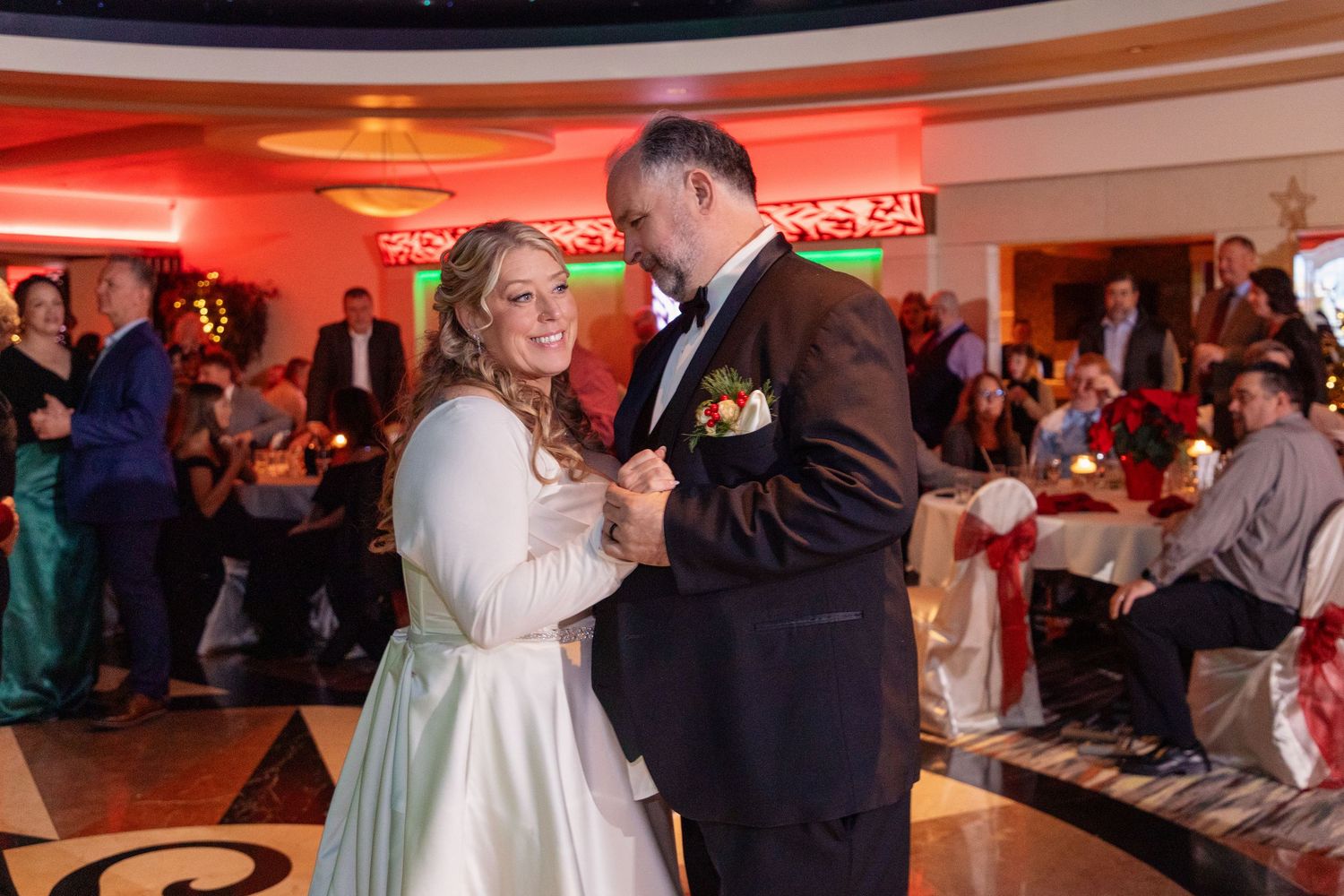 Wedding reception dance floor with red ambient lighting and guests dancing.