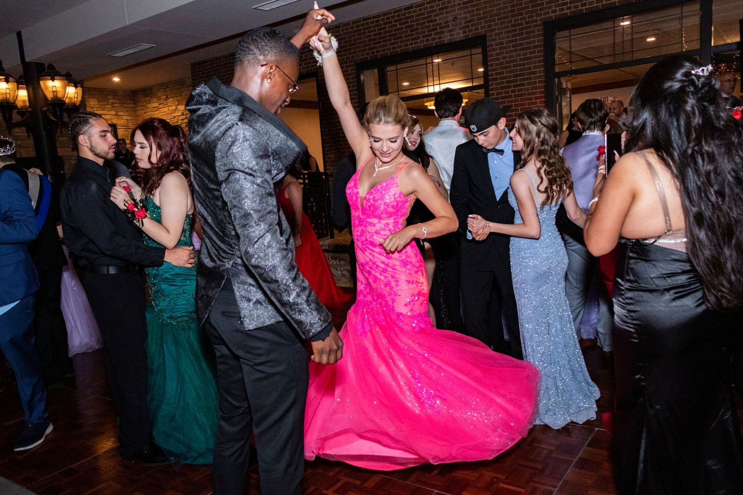 Couples dancing and celebrating at a lively wedding reception with colorful formal attire.