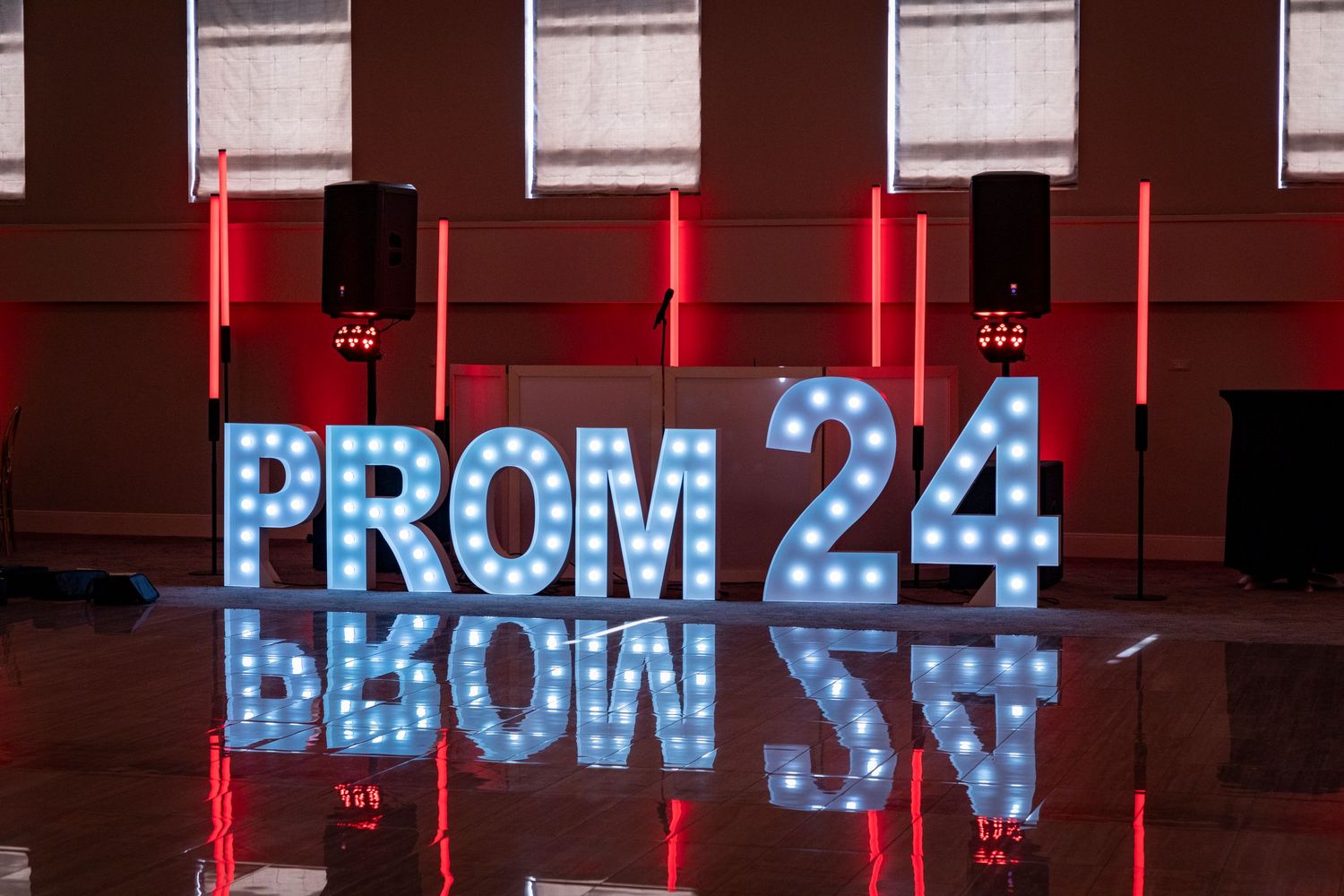 Illuminated blue neon sign displaying 'PROM 24' text on a red wall.
