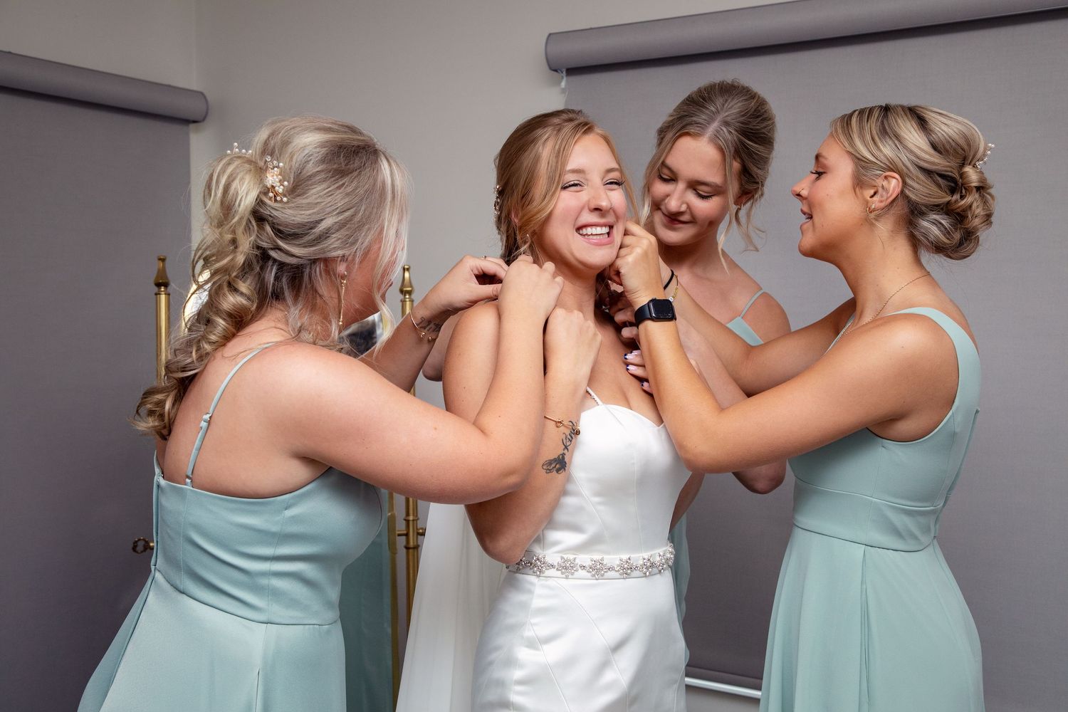 Bridesmaids in mint dresses share a joyful moment with the bride during wedding preparations.