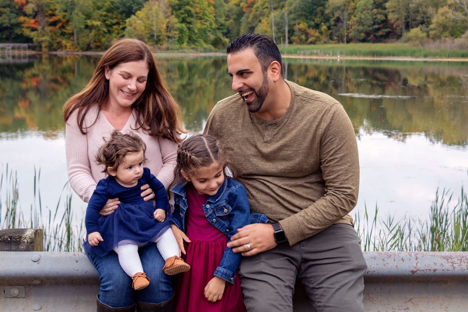 Family enjoying a playful moment together by a serene lake on an autumn day.