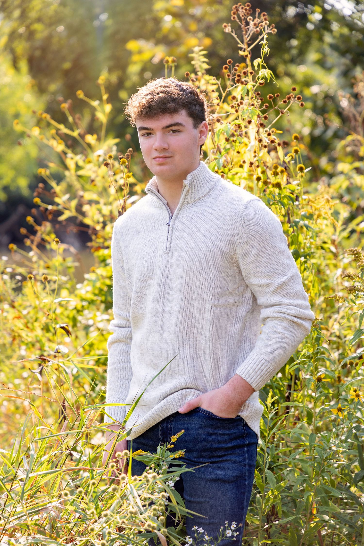 Casual autumn portraits in cream quarter-zip sweater among golden foliage.