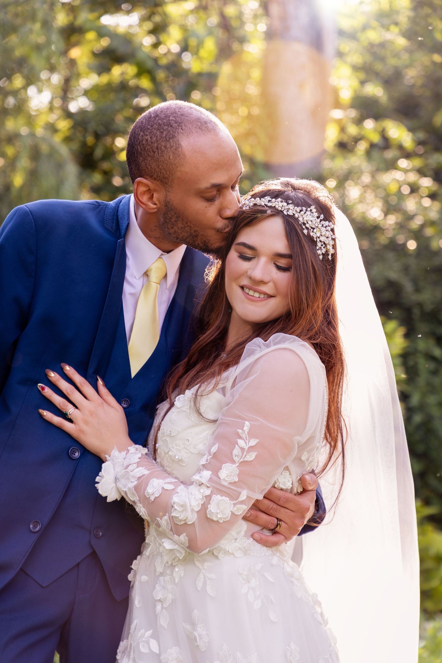 A tender moment between newlyweds in a sunlit garden setting.