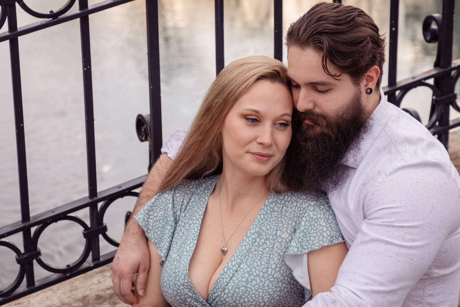Romantic couple embraces against decorative iron fence backdrop.