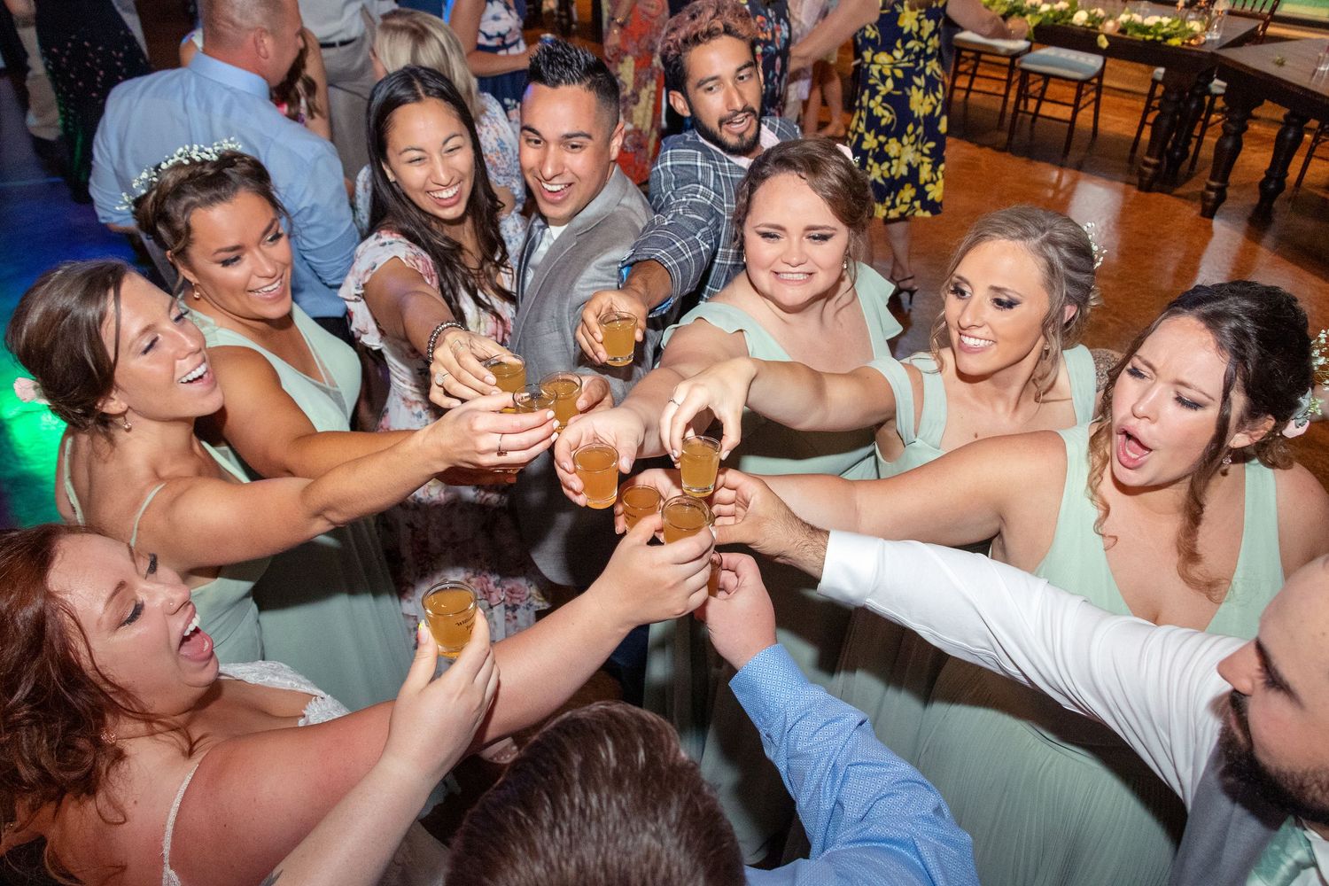 Wedding party celebrating with shots in a circle during the reception party.