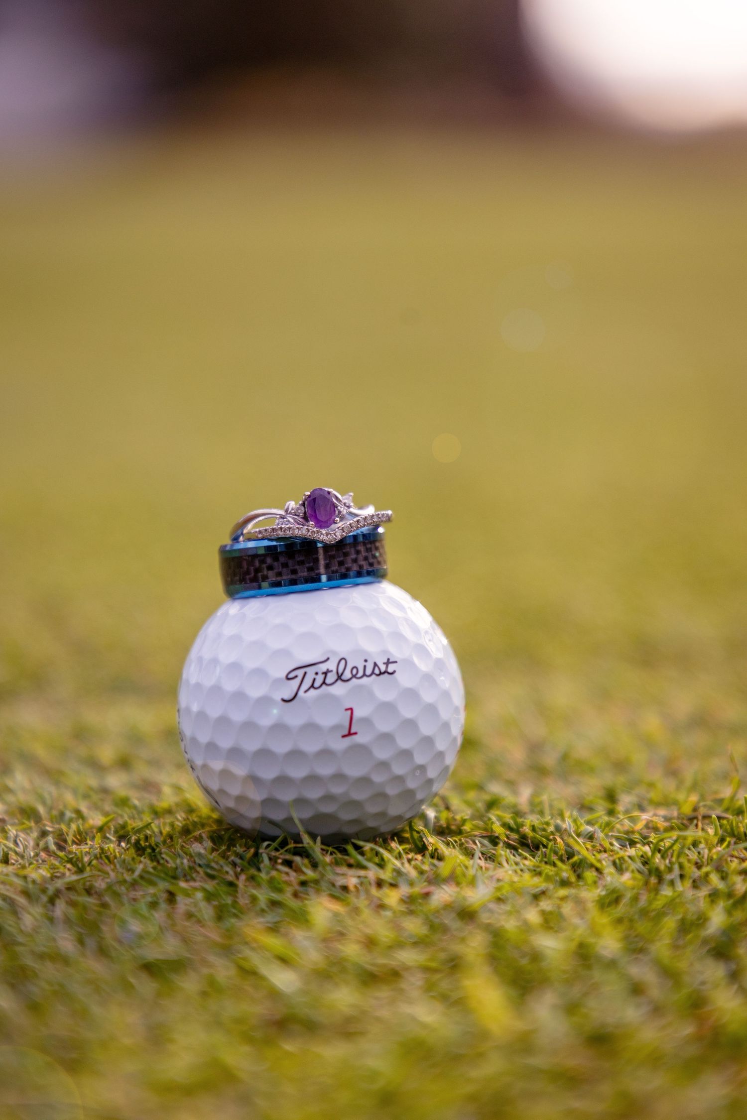 Wedding rings photographed on white golf balls in grass.