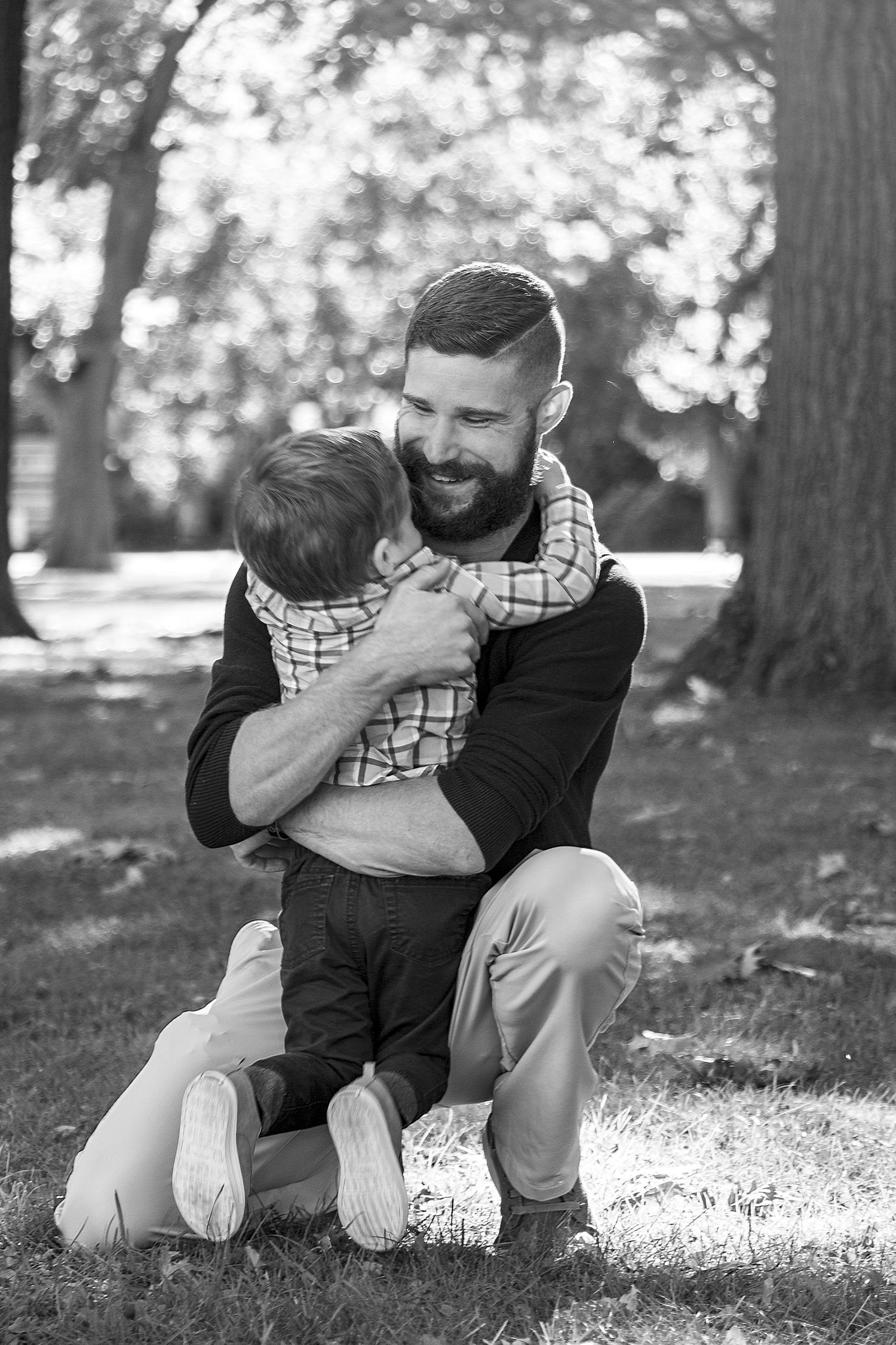 Black and white portrait of tender family moments in a park setting.