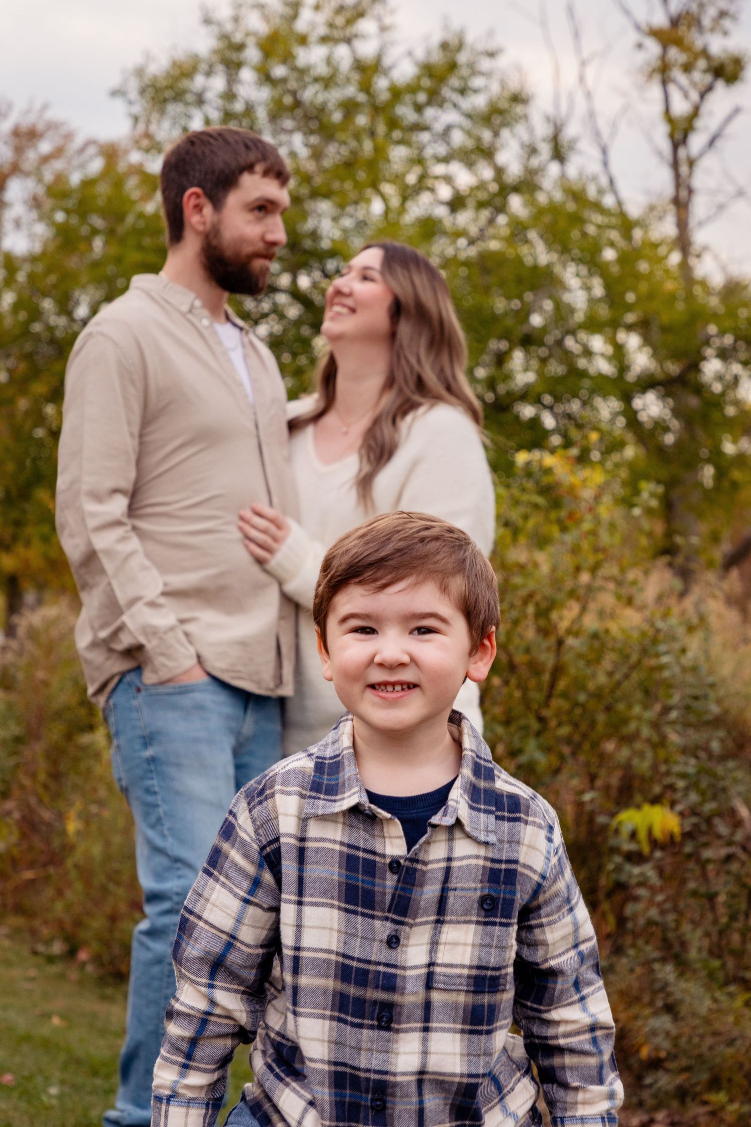 Family portrait session in a park with vibrant fall colors and natural lighting.