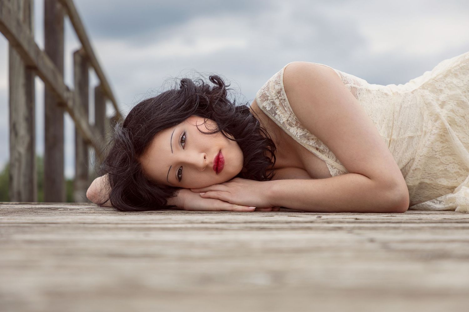 Artistic portrait series laying on wooden deck with soft natural lighting.