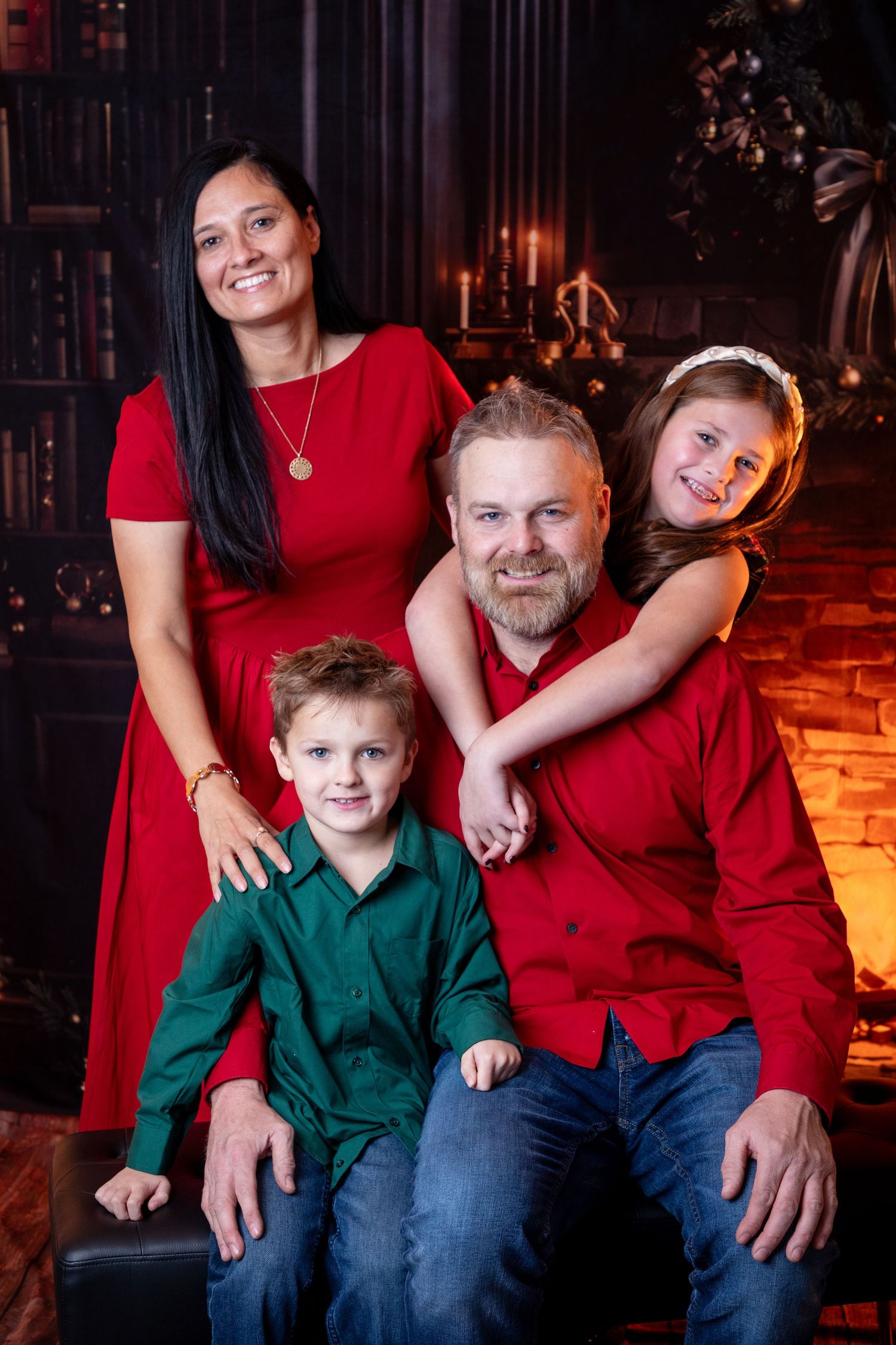 Indoor family portrait with festive red and green outfits in front of warm lighting.
