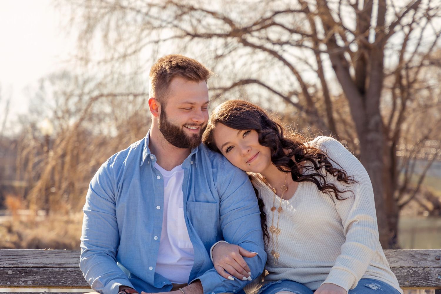 A couple relaxes together on a dock by a winter lake scene.