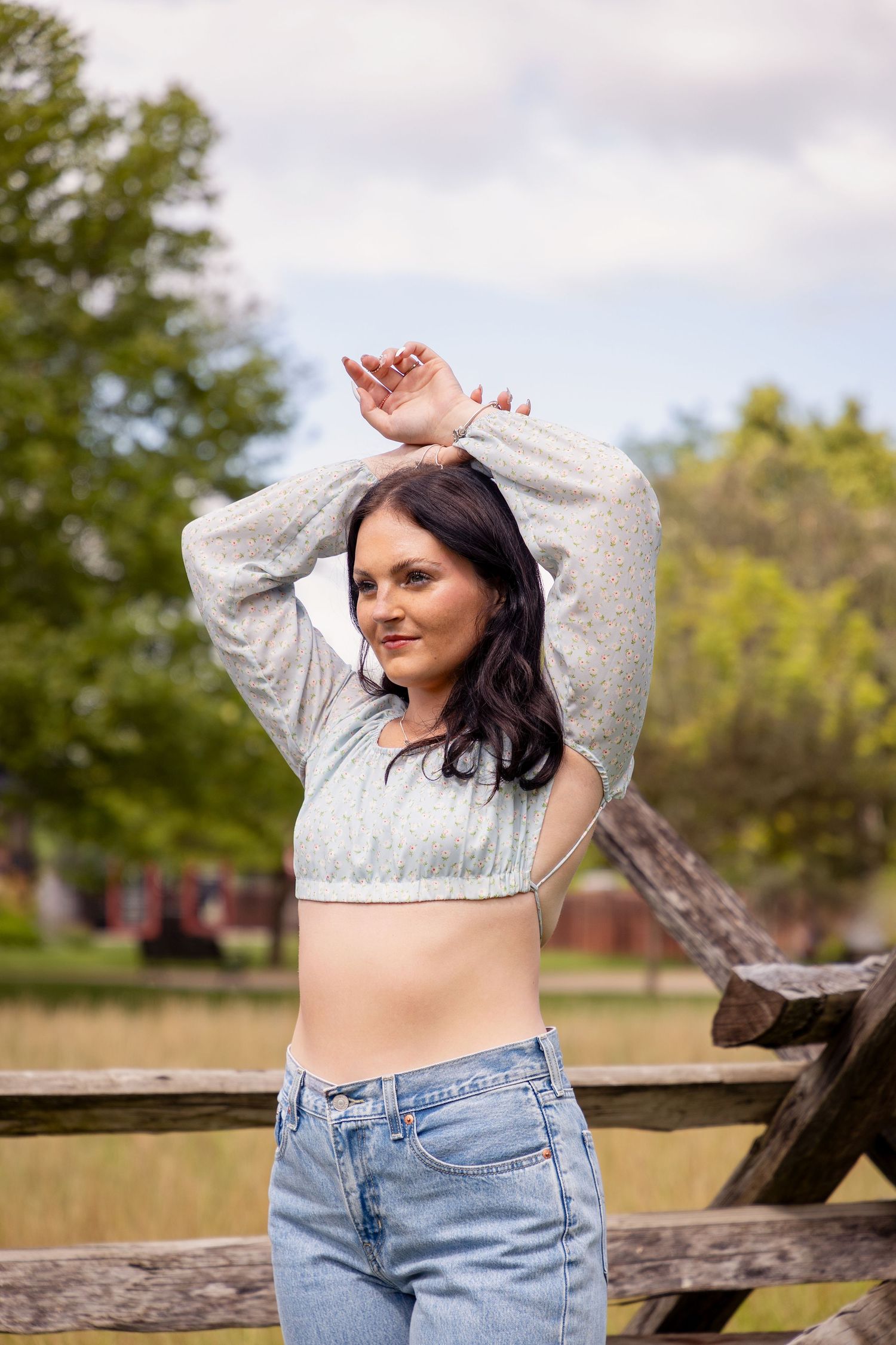 Casual outdoor photoshoot by wooden fence in natural lighting.