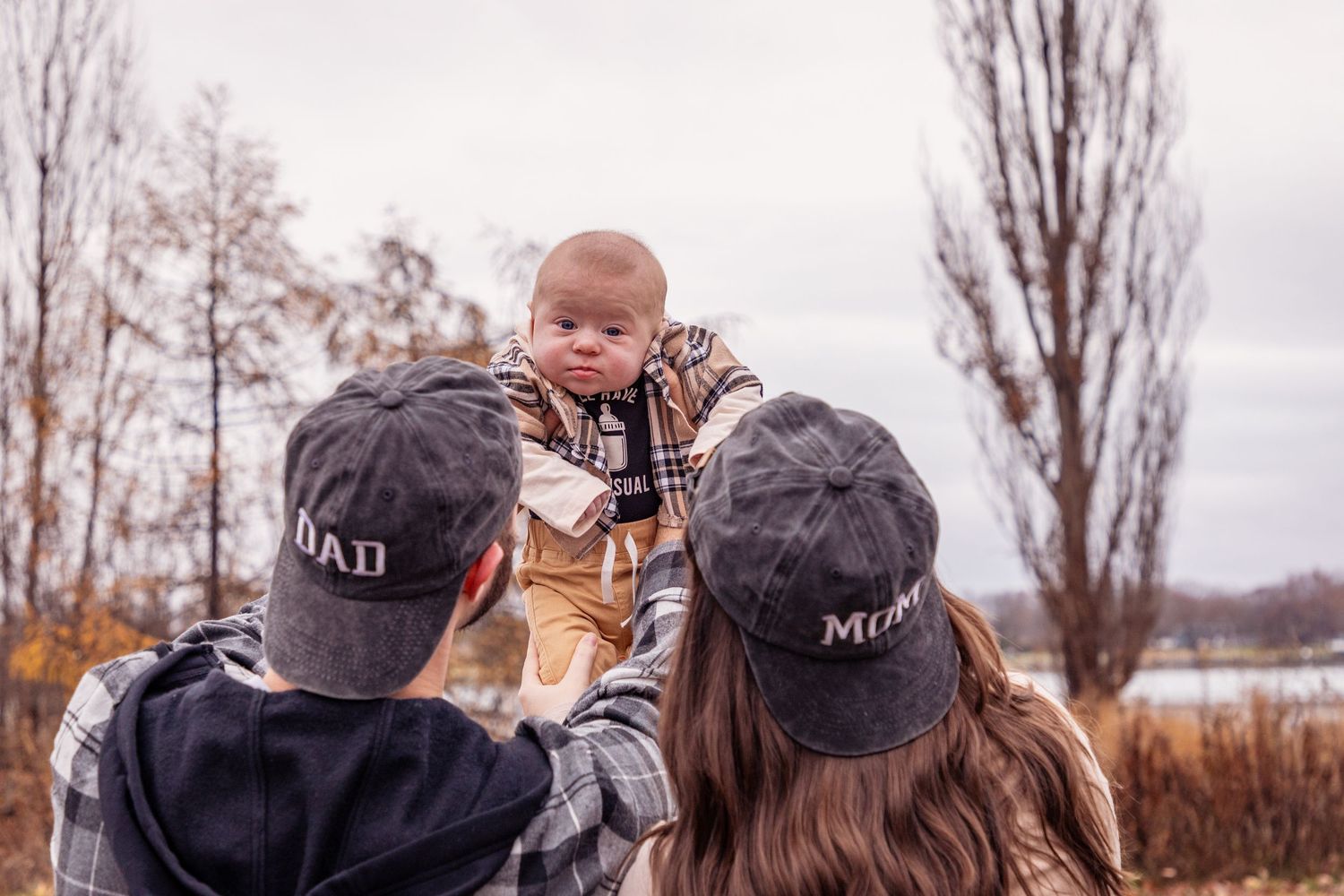 Winter outdoor photoshoot on cloudy day with bare trees in background.