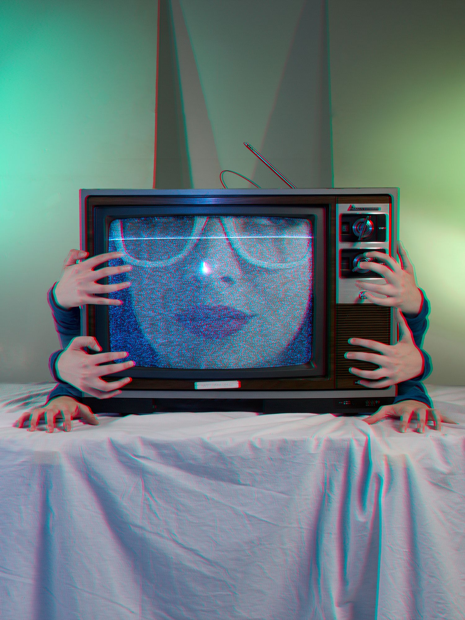 Hands holding a dark rectangular frame against a teal background.
