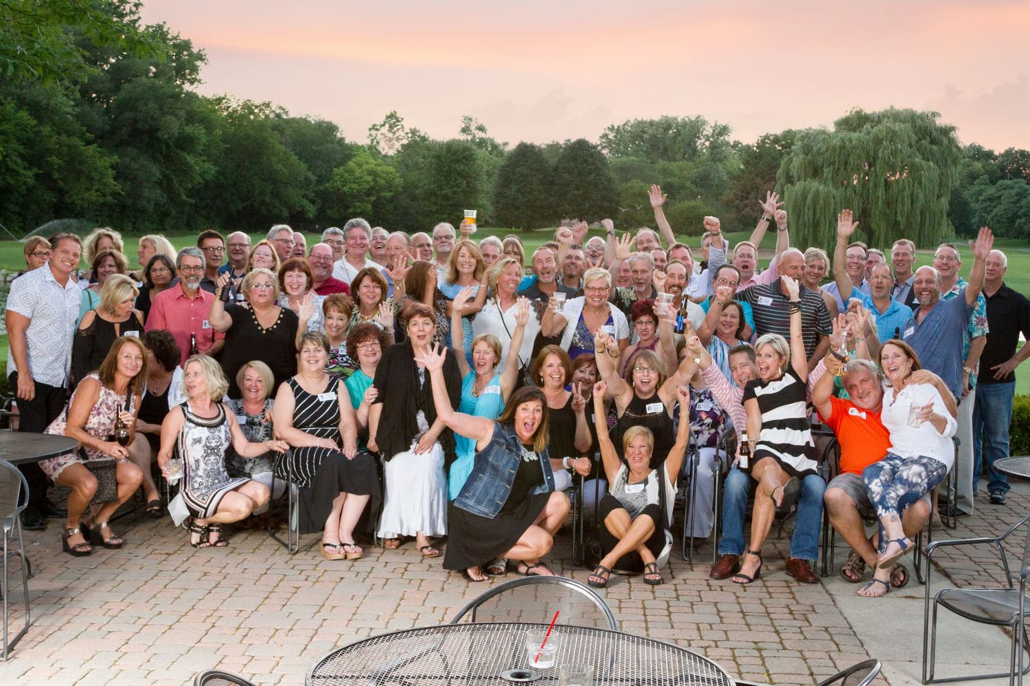 Large outdoor group photo of wedding guests at sunset.