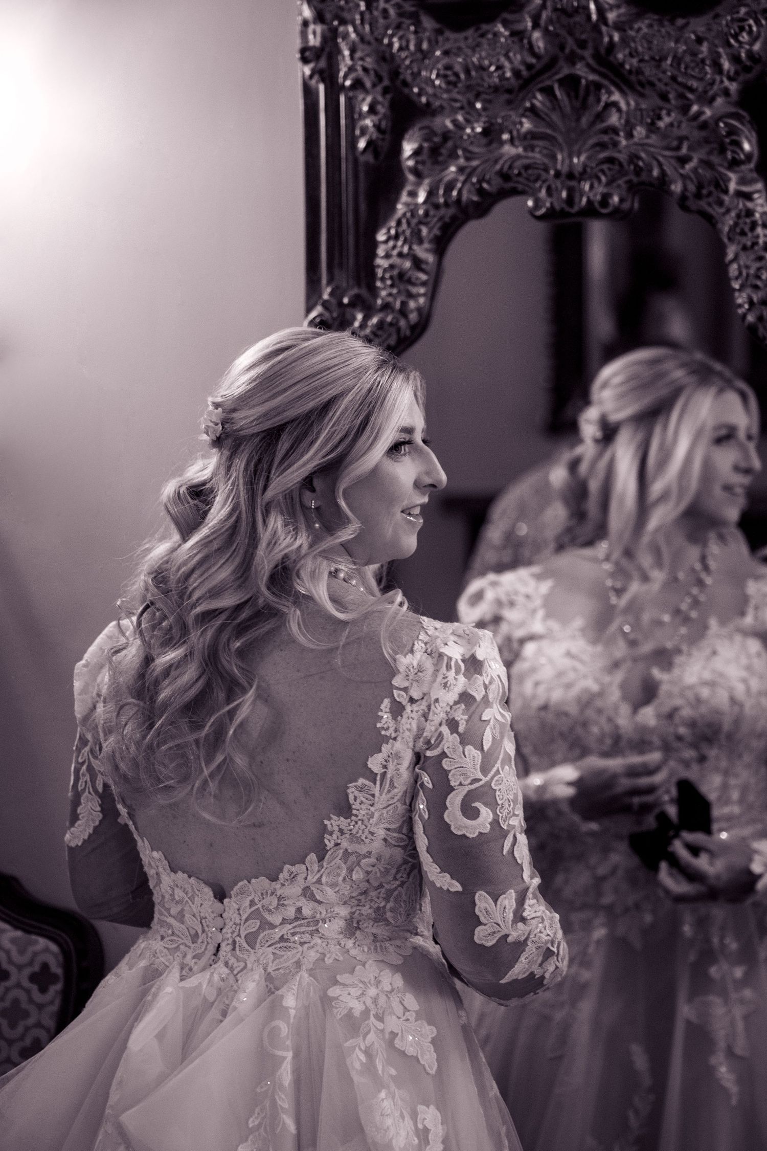 Elegant black and white portrait of bride in lace wedding gown with intricate details.