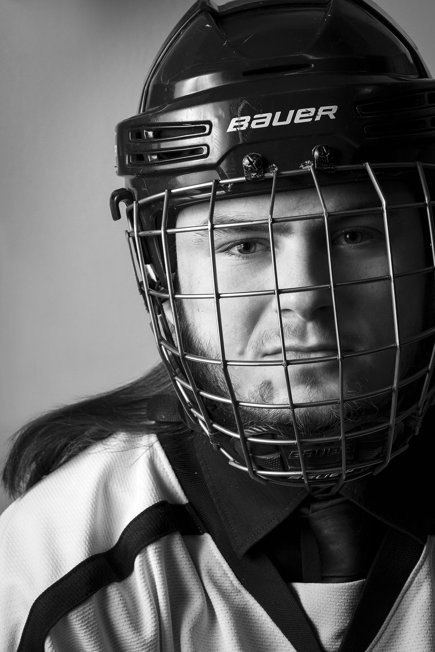 Black and white portraits of hockey players wearing Bauer helmets with face guards.