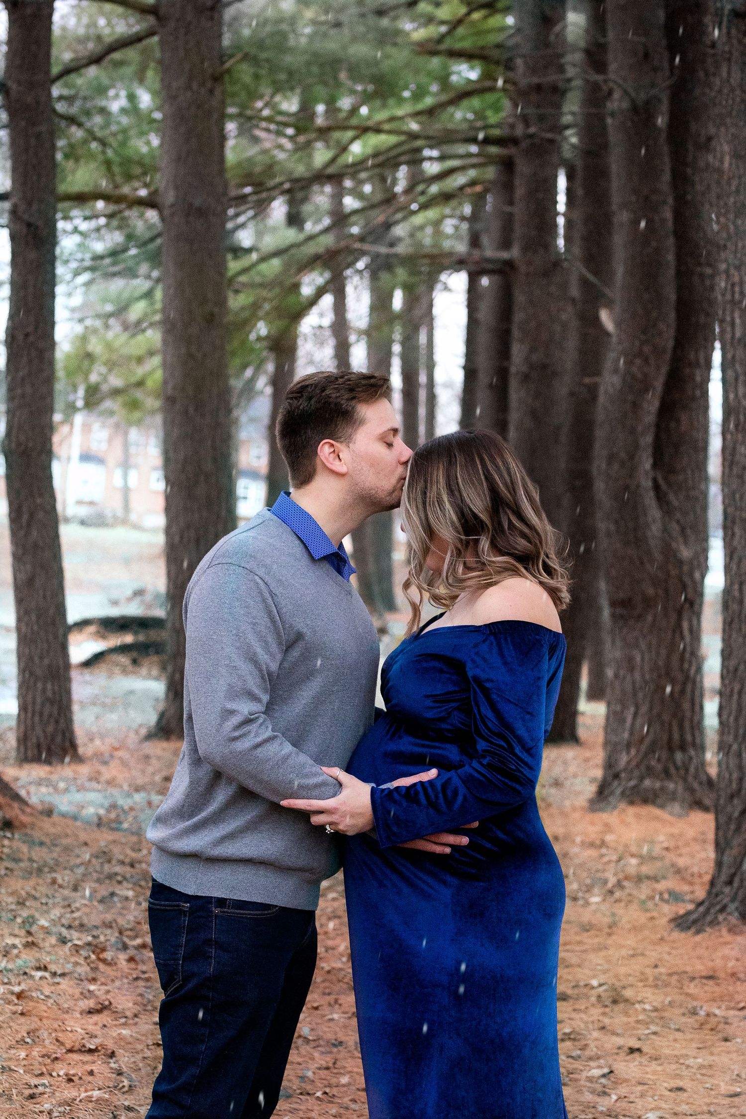 Romantic forest maternity session among tall pine trees.