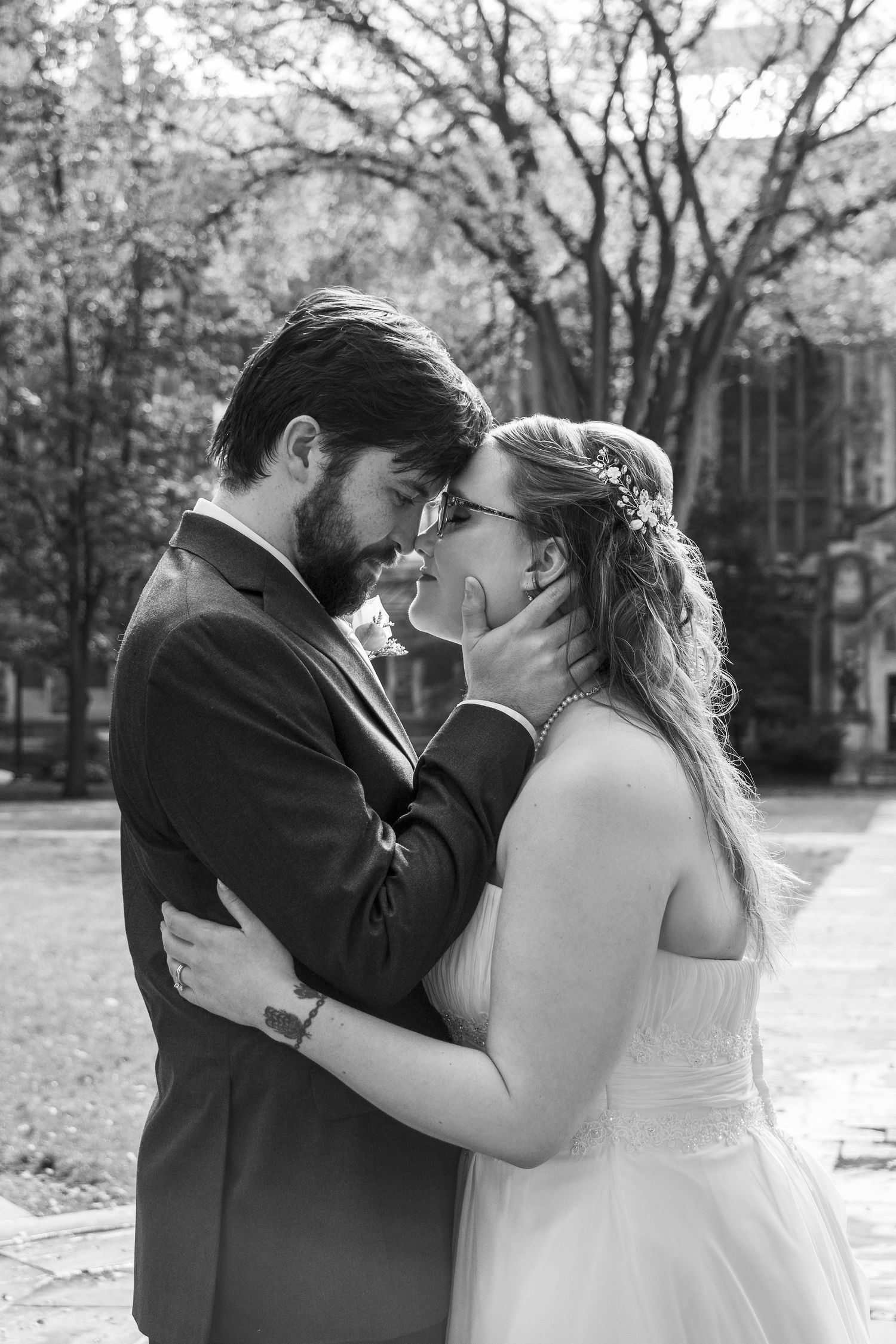 A romantic black and white portrait of a couple sharing an intimate wedding moment outdoors.