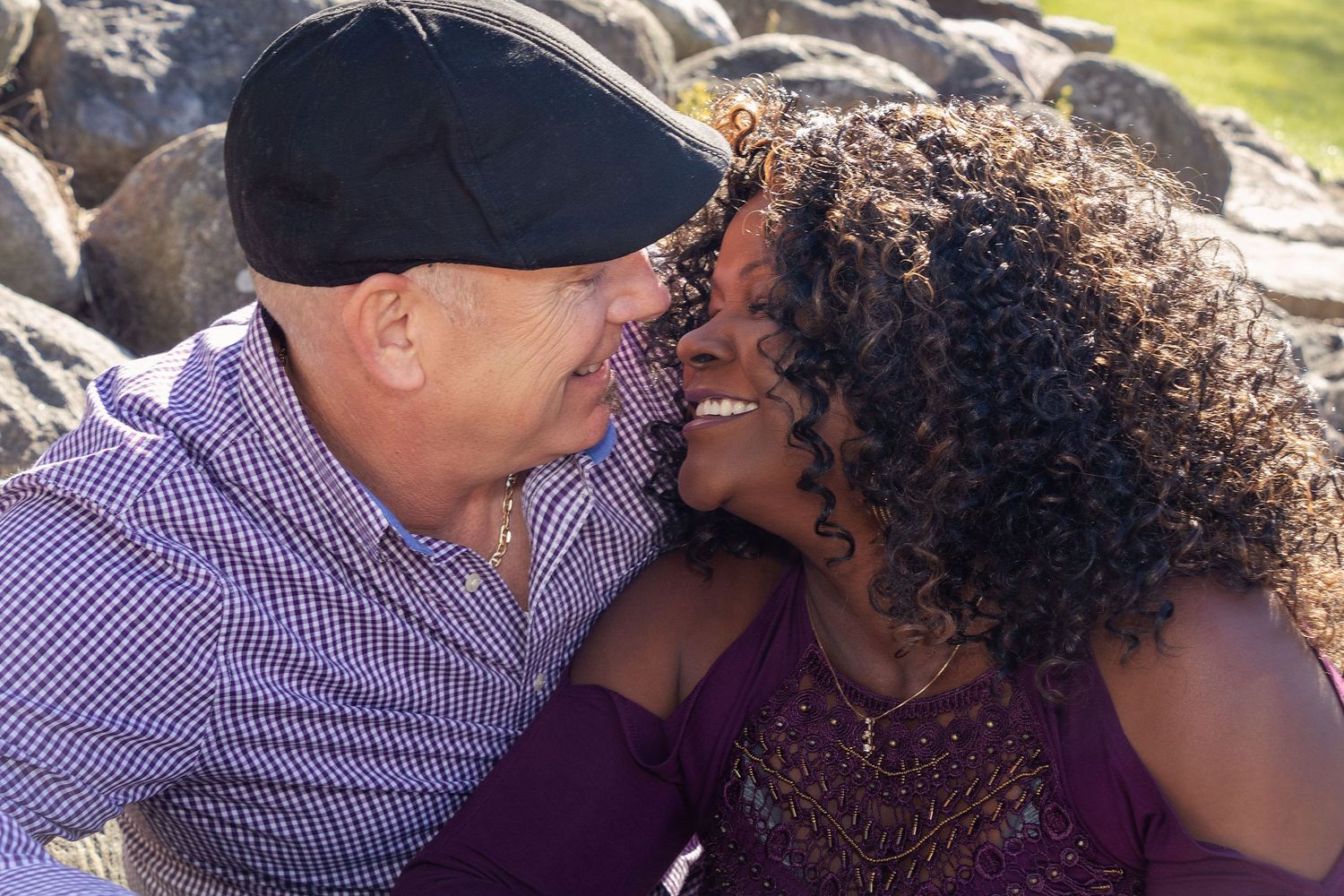 A couple shares an intimate moment outdoors against a backdrop of autumn foliage.