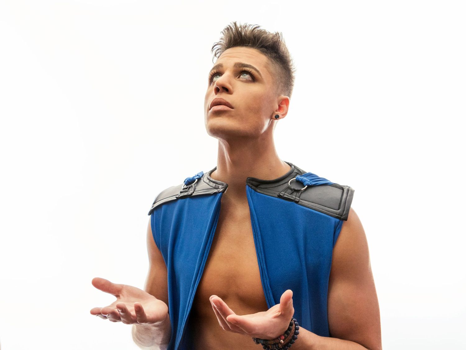 A dramatic portrait of someone wearing a blue sleeveless vest against a white background.
