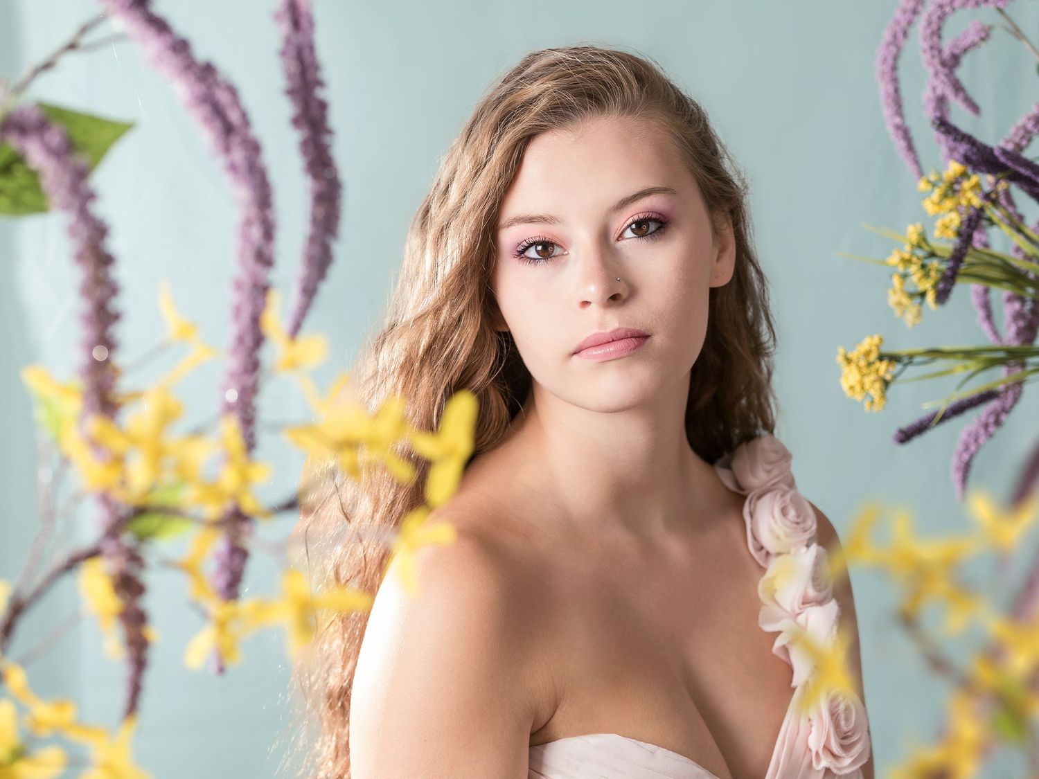 Ethereal spring portrait with pink and yellow flowers in soft lighting.