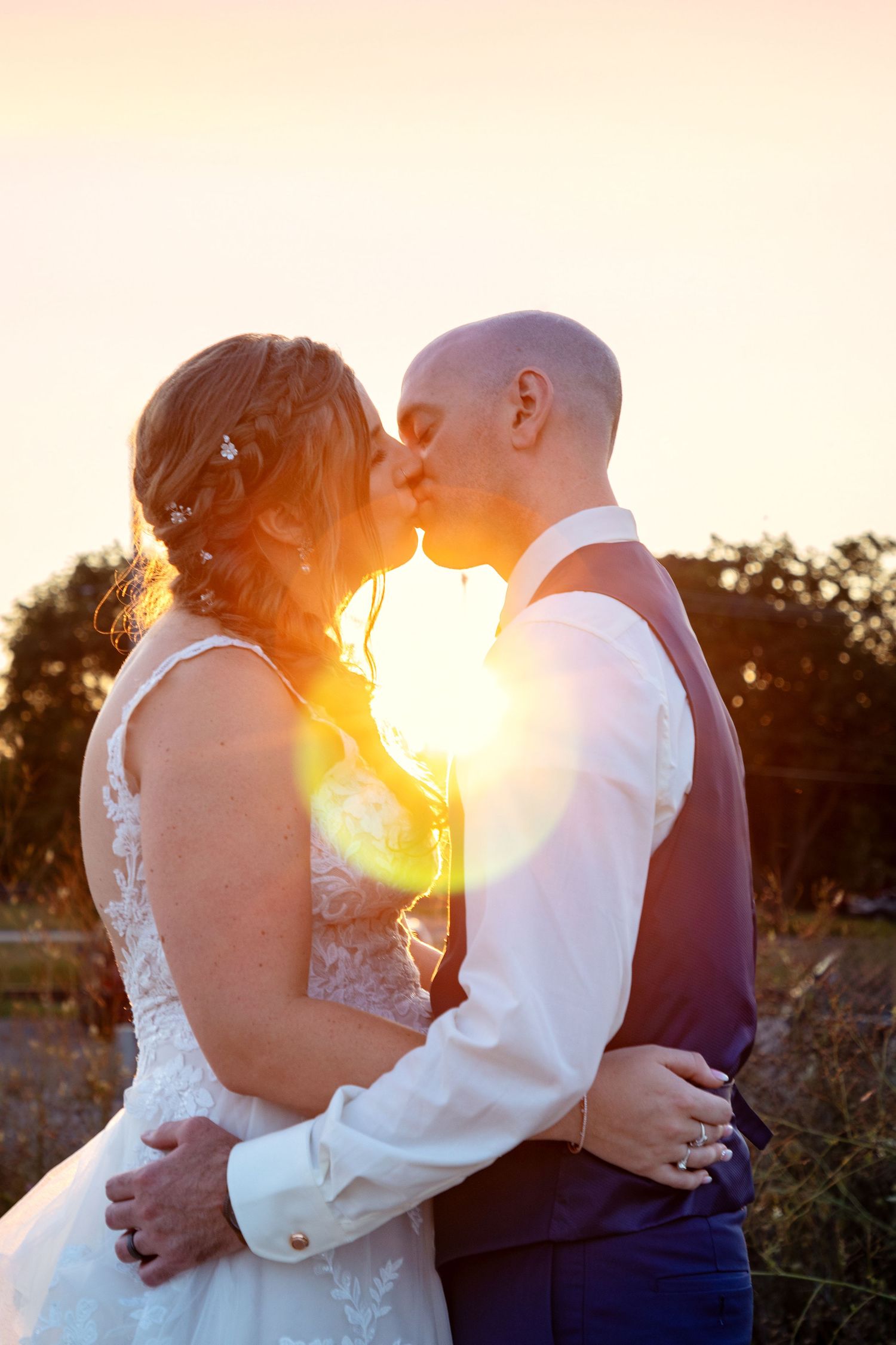 Romantic sunset silhouette of couple embracing during golden hour wedding photos.