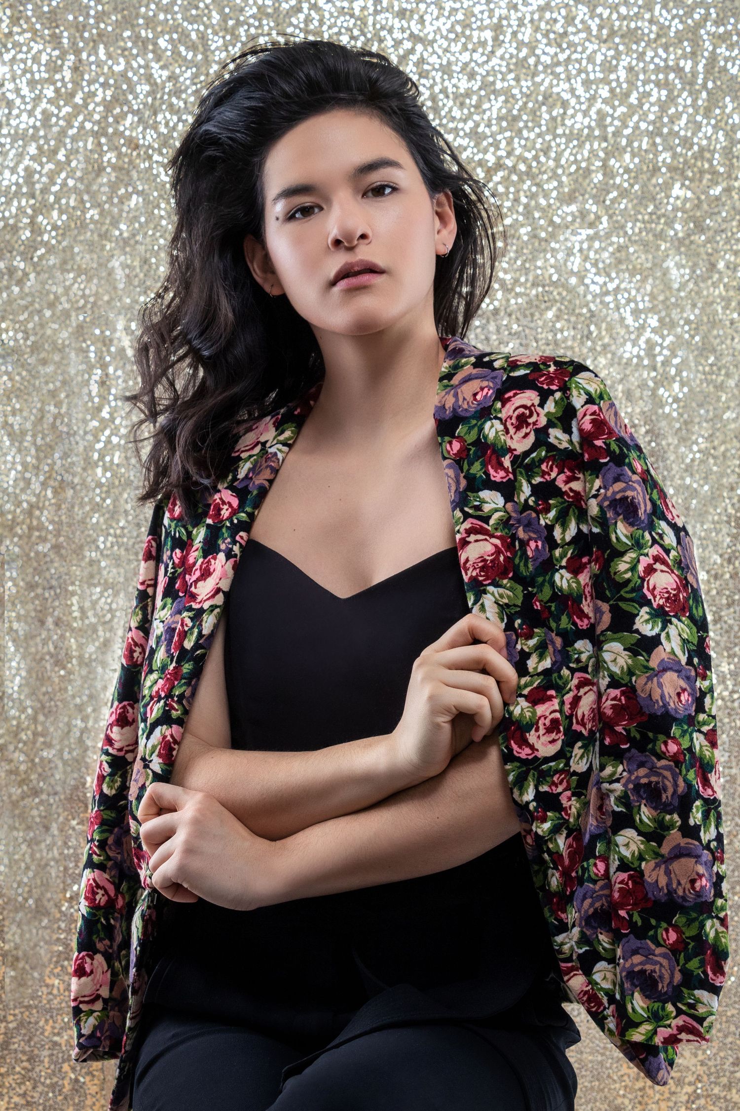 Fashion portraits against sparkly backdrop wearing floral print jacket and black top.