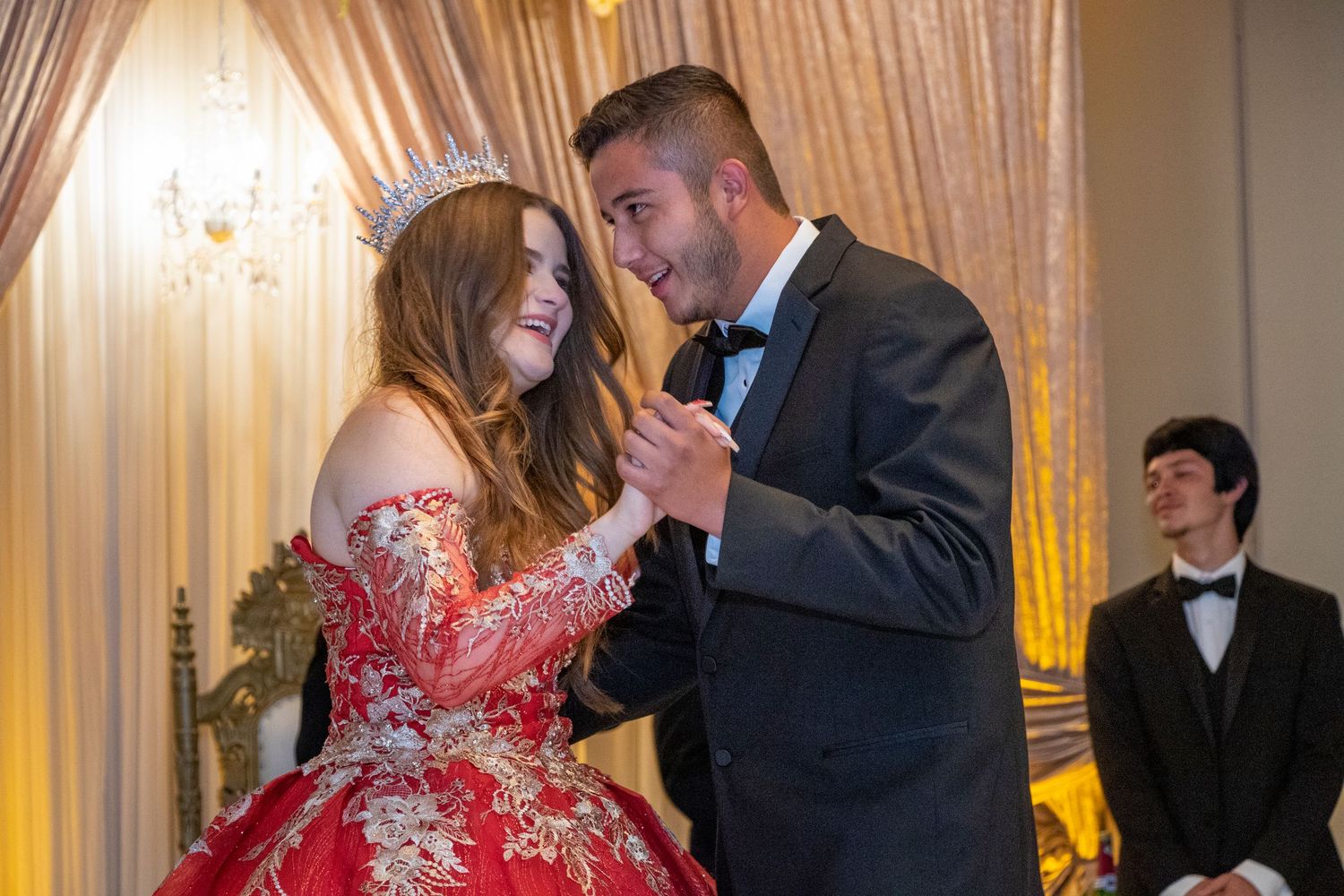 A formal dance scene with elegant dresses and suits in a banquet hall setting.