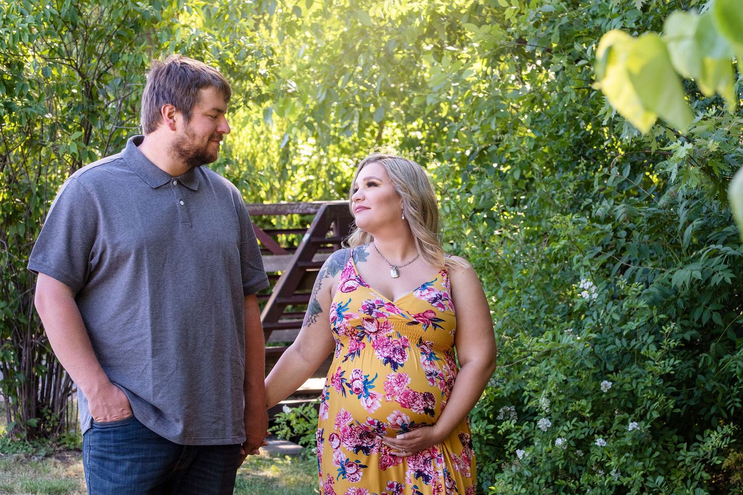 Couple sharing intimate moments in a lush green garden setting.