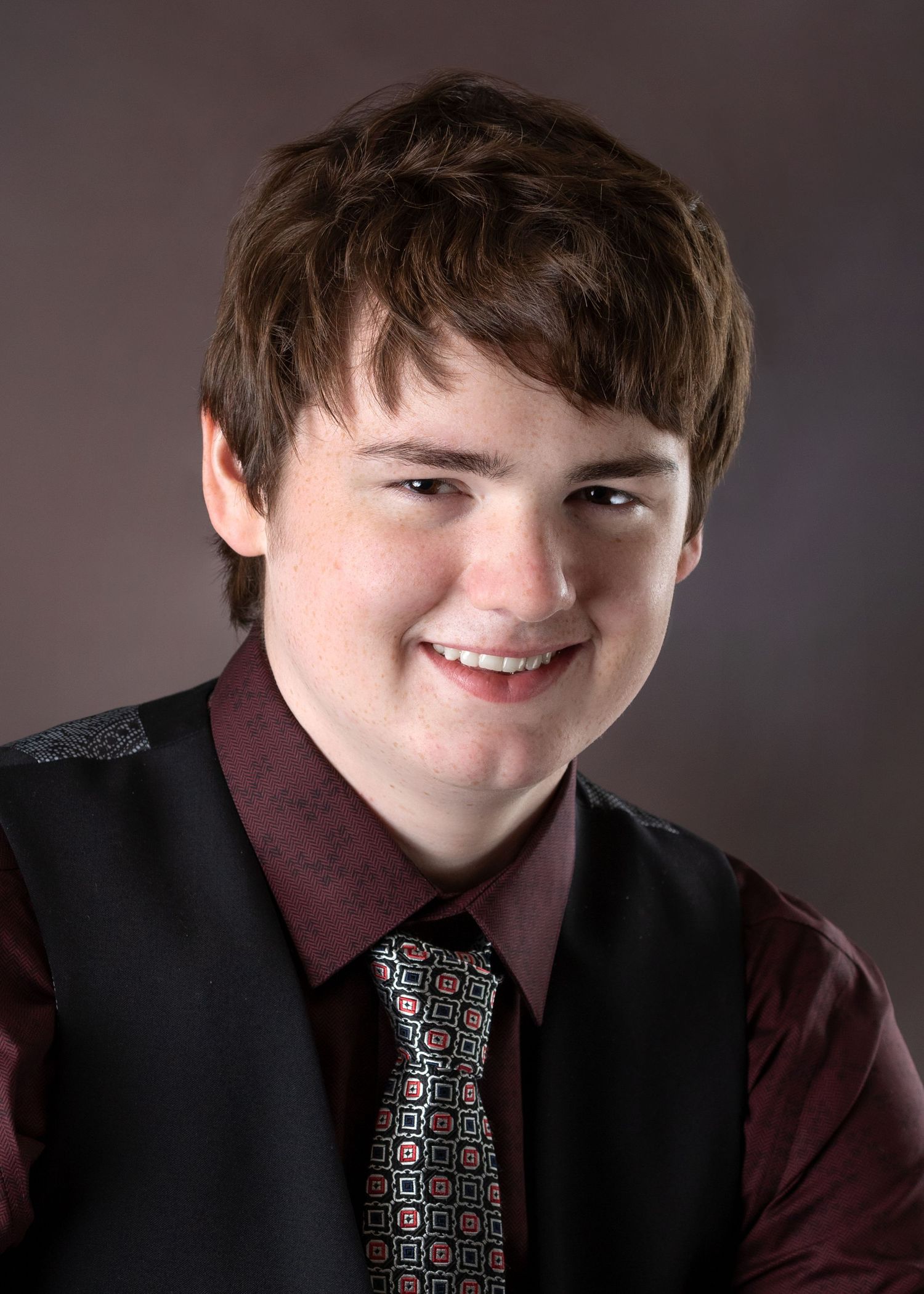 Studio portrait series showing someone in black vest and patterned tie against dark backdrop.
