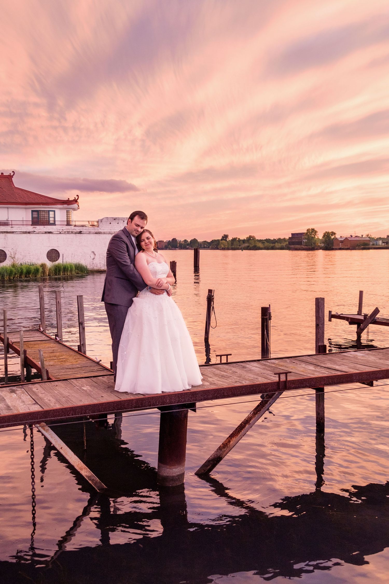 Sunset wedding portraits on a wooden dock over calm water.