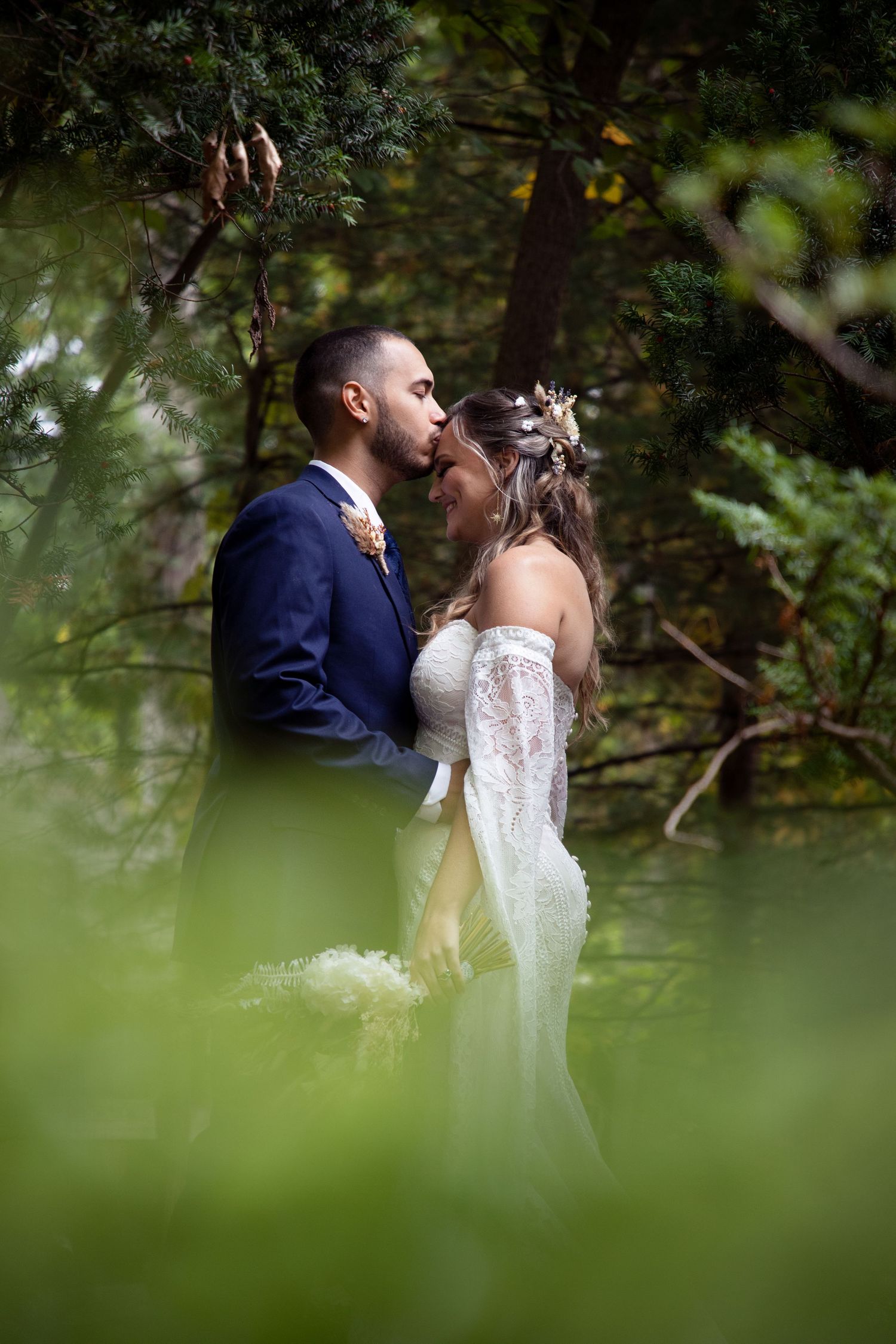 Romantic wedding couple shares intimate moments in a lush garden setting with natural greenery.