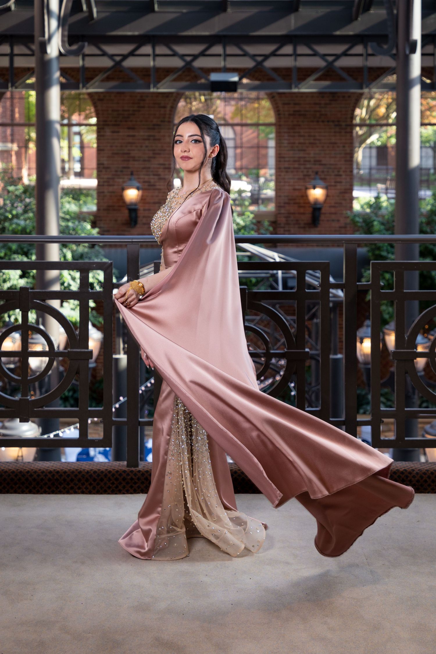 A flowing pink dress twirls gracefully against an industrial brick and metal backdrop.