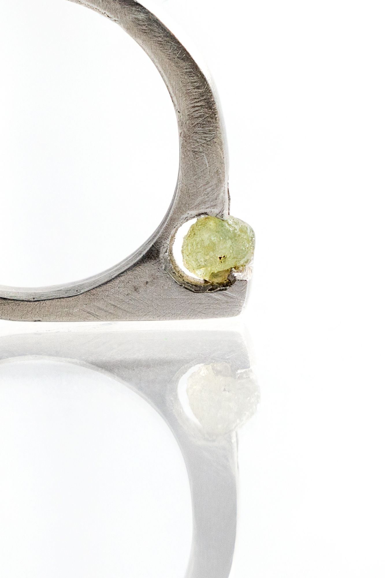 Close-up view of minimalist silver rings with gemstones on white surface.