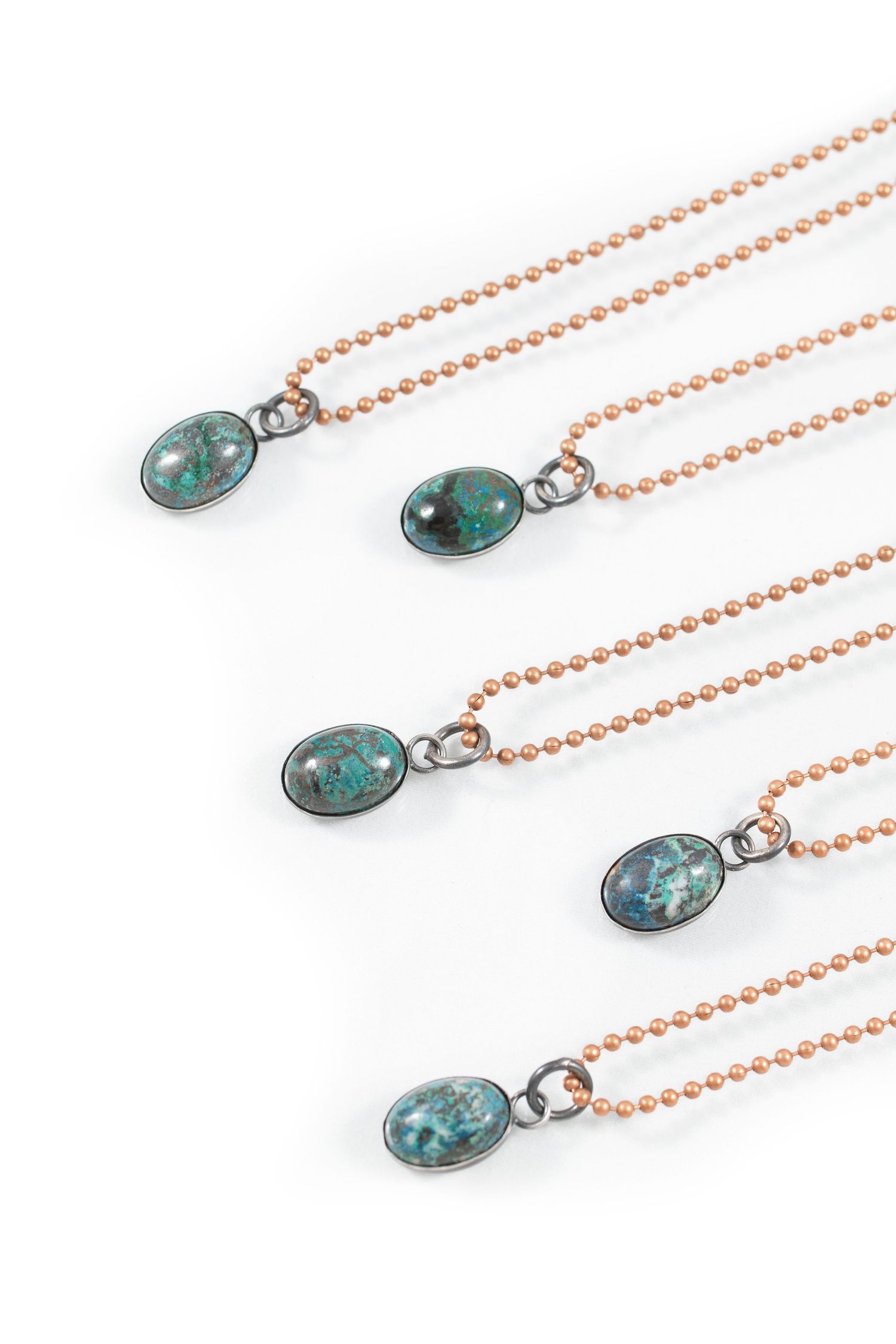 Turquoise stone pendants on copper ball chain necklaces against white background.