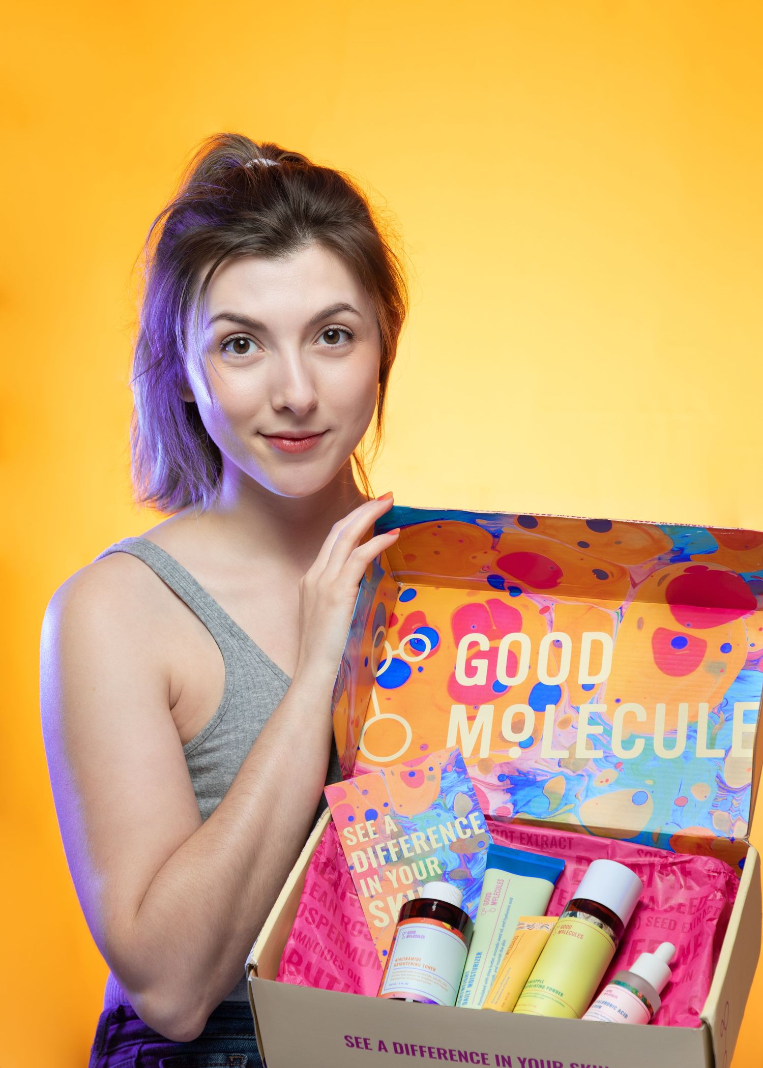 Colorful beauty product packaging displayed against vibrant orange background.
