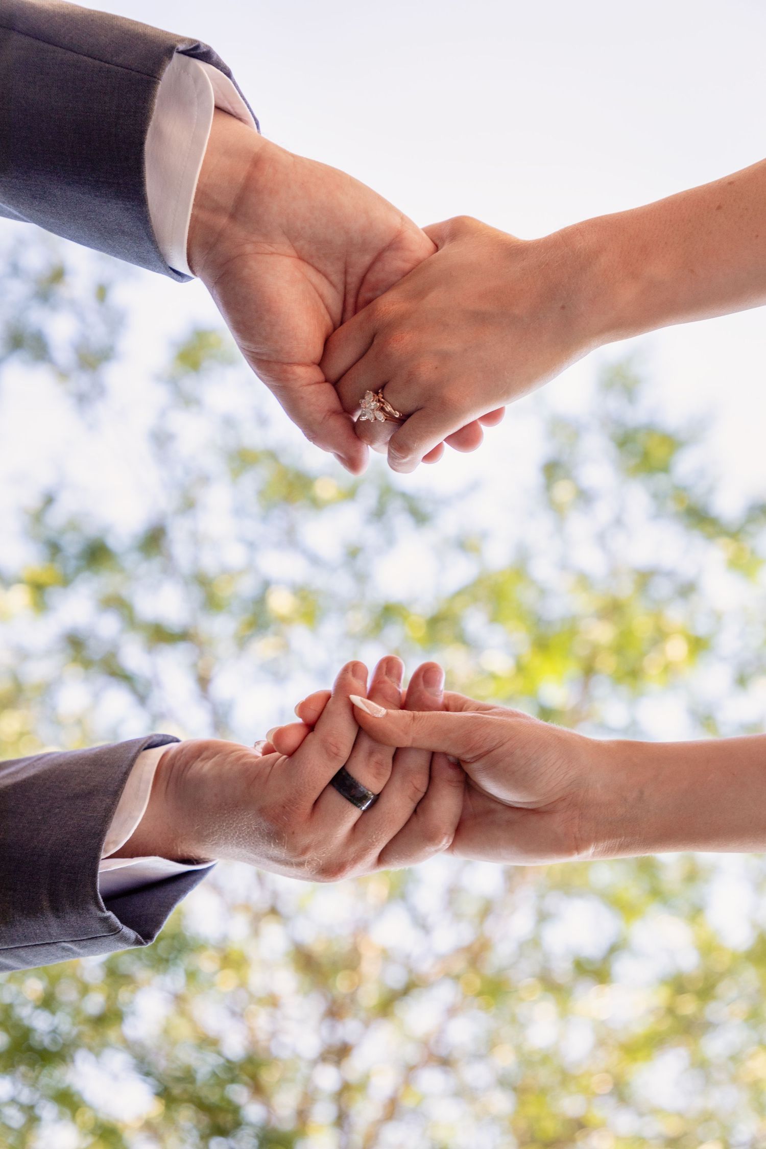 Series of hands exchanging rings during wedding ceremony with natural backdrop.