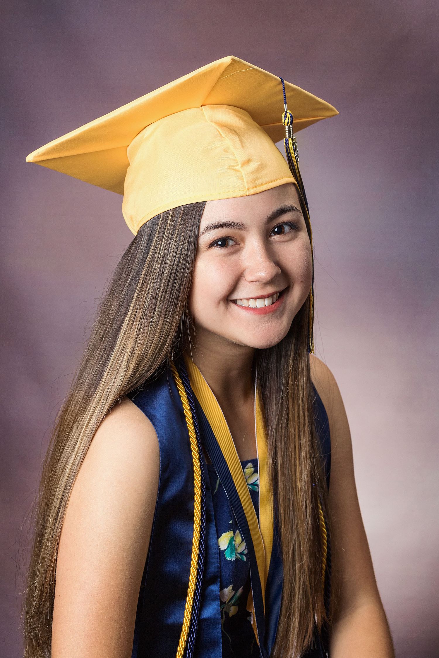 Graduate in gold cap and navy gown poses for series of portraits.