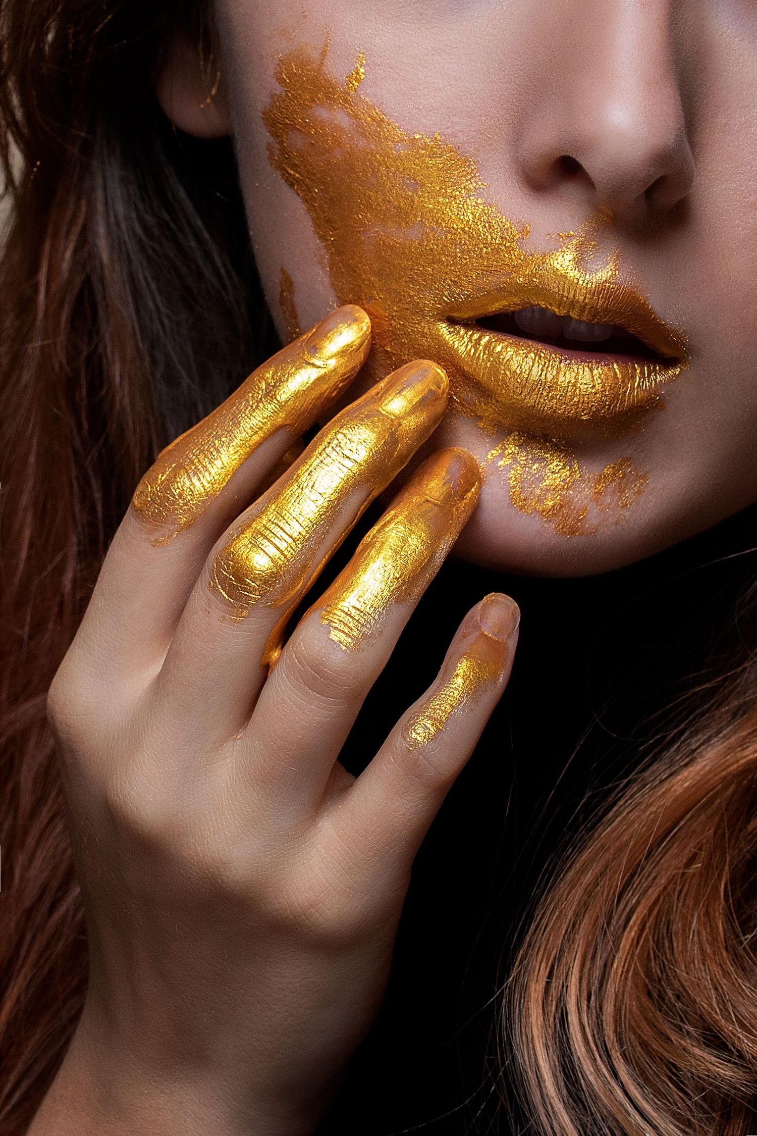 Artistic beauty shot featuring shimmering gold makeup and metallic hand details.
