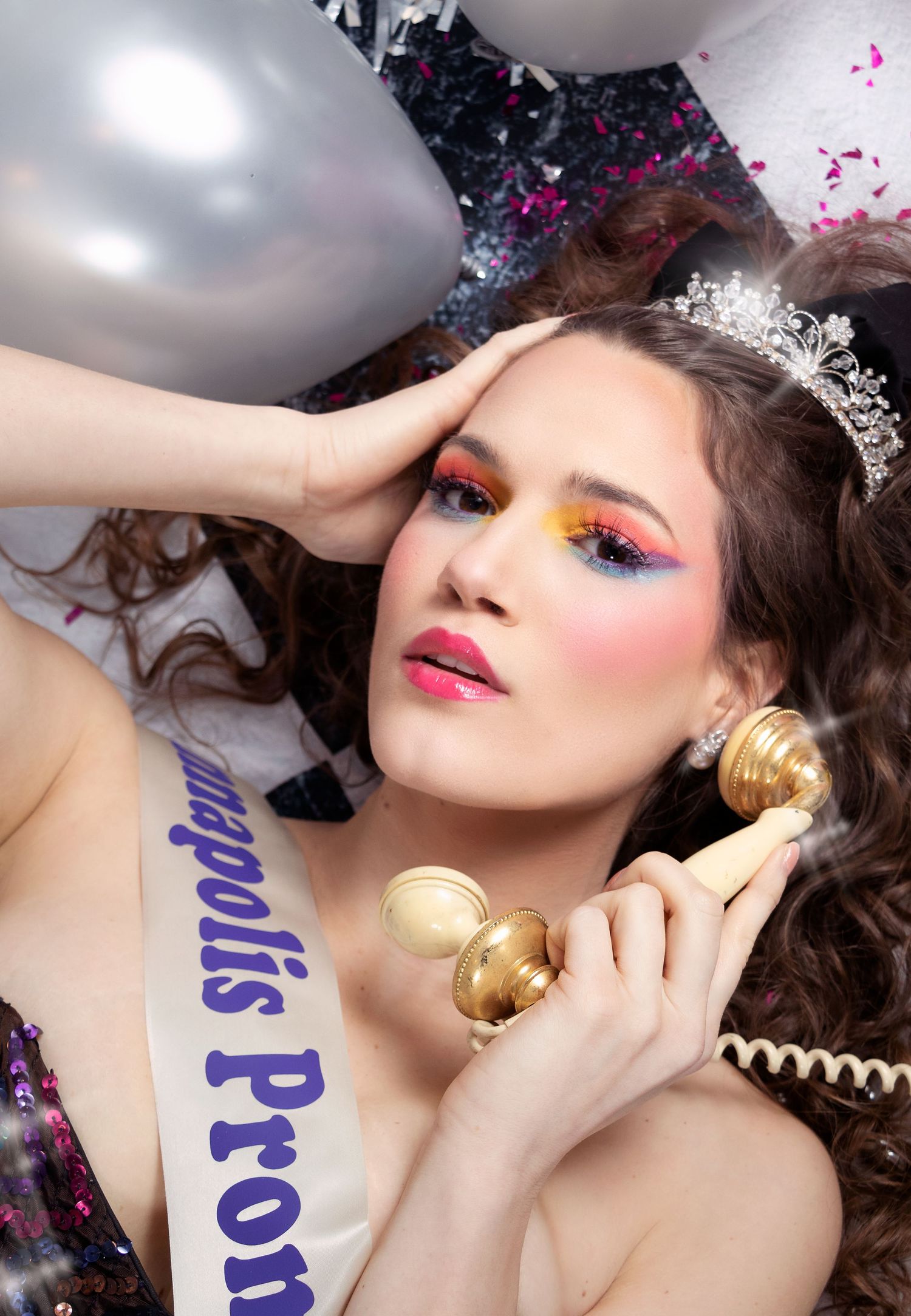 Artistic beauty portrait with silver balloons and dramatic makeup against dark background.