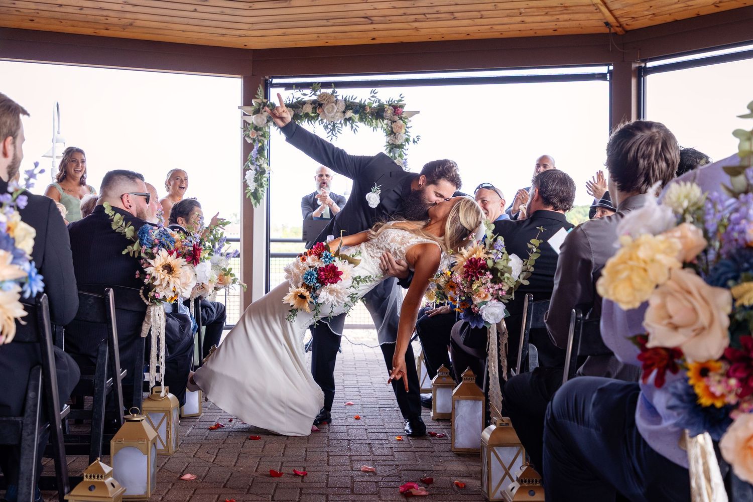 Wedding ceremony exit with guests cheering in covered outdoor venue.