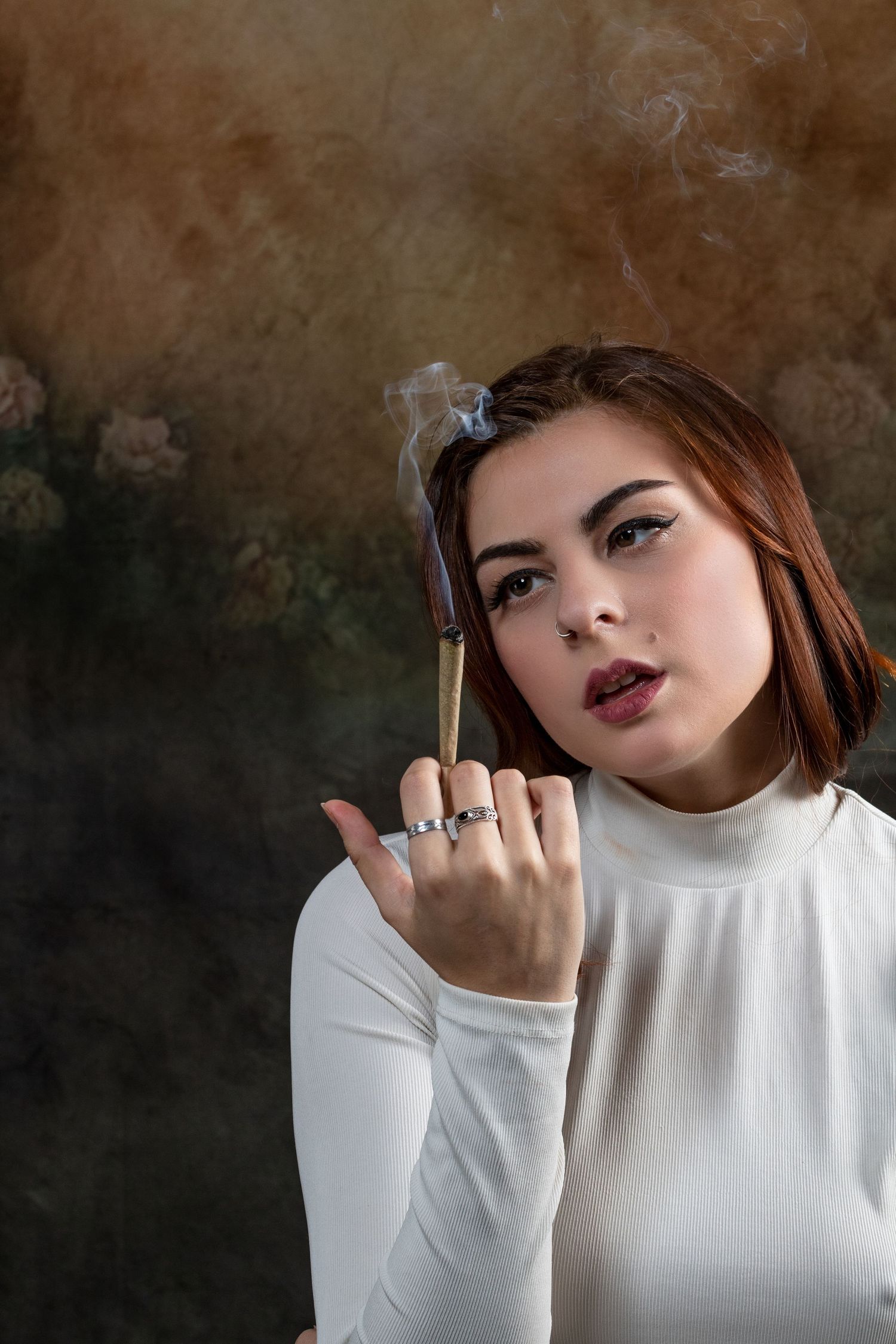 Moody portrait series in white turtleneck showing dramatic makeup against textured brown background.
